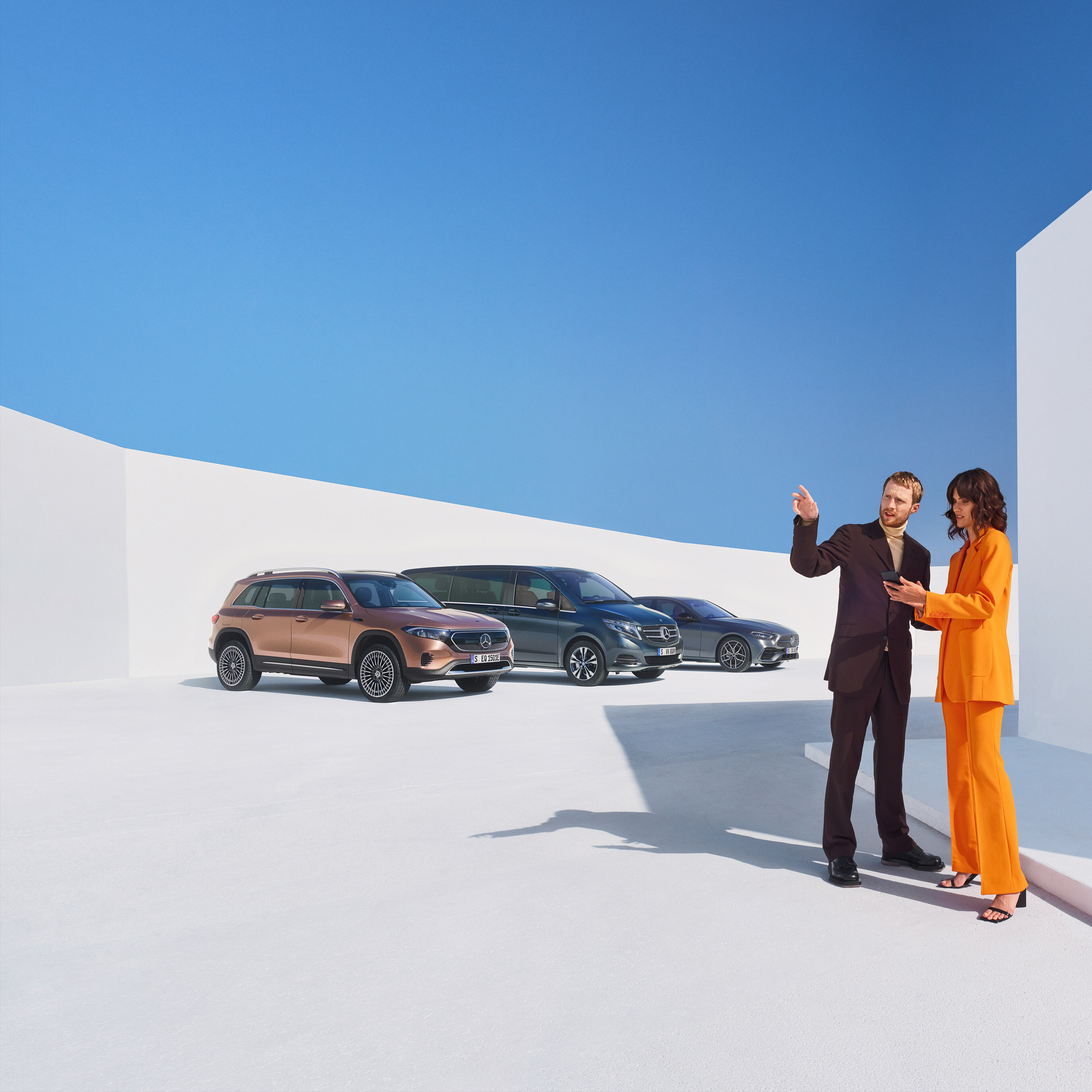 Dos personas hablando sobre los Extras Digitales para clientes profesionales. En el fondo se pueden ver tres vehículos Mercedes-Benz.