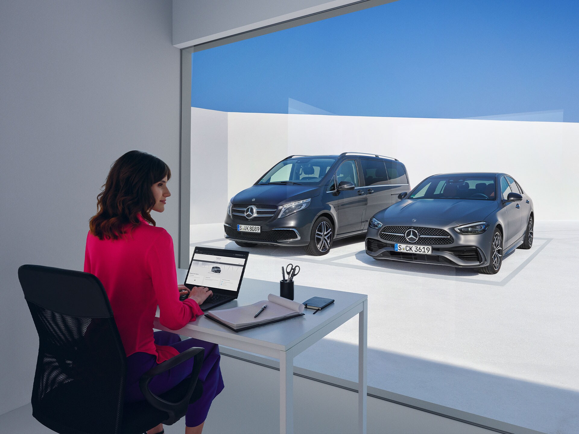 Mujeres sentadas delante del Mercedes-Benz Clase V y Clase C, mirando un ordenador portátil.