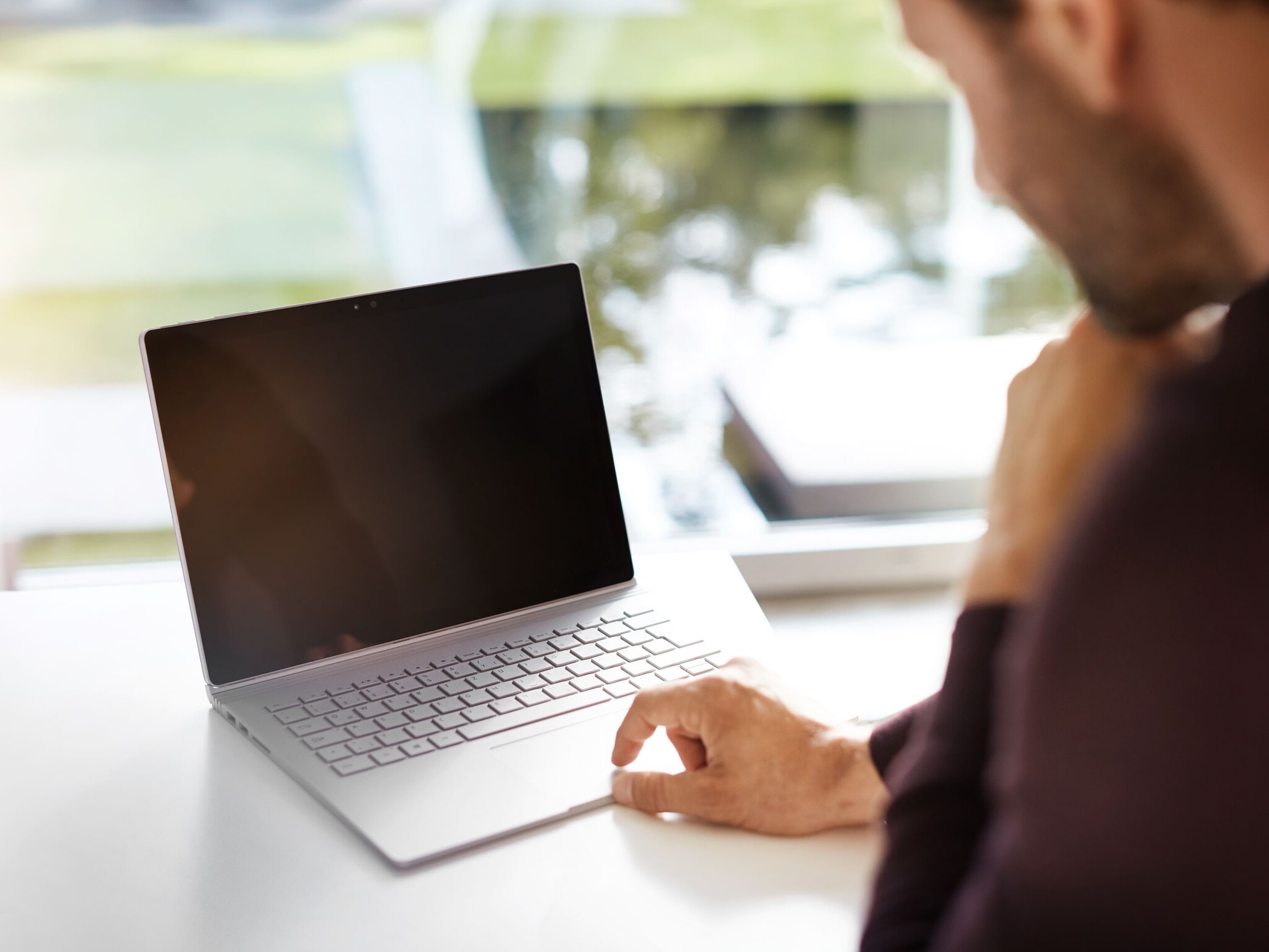Primer plano de un ordenador portátil sobre un escritorio con una persona acercándose a él
