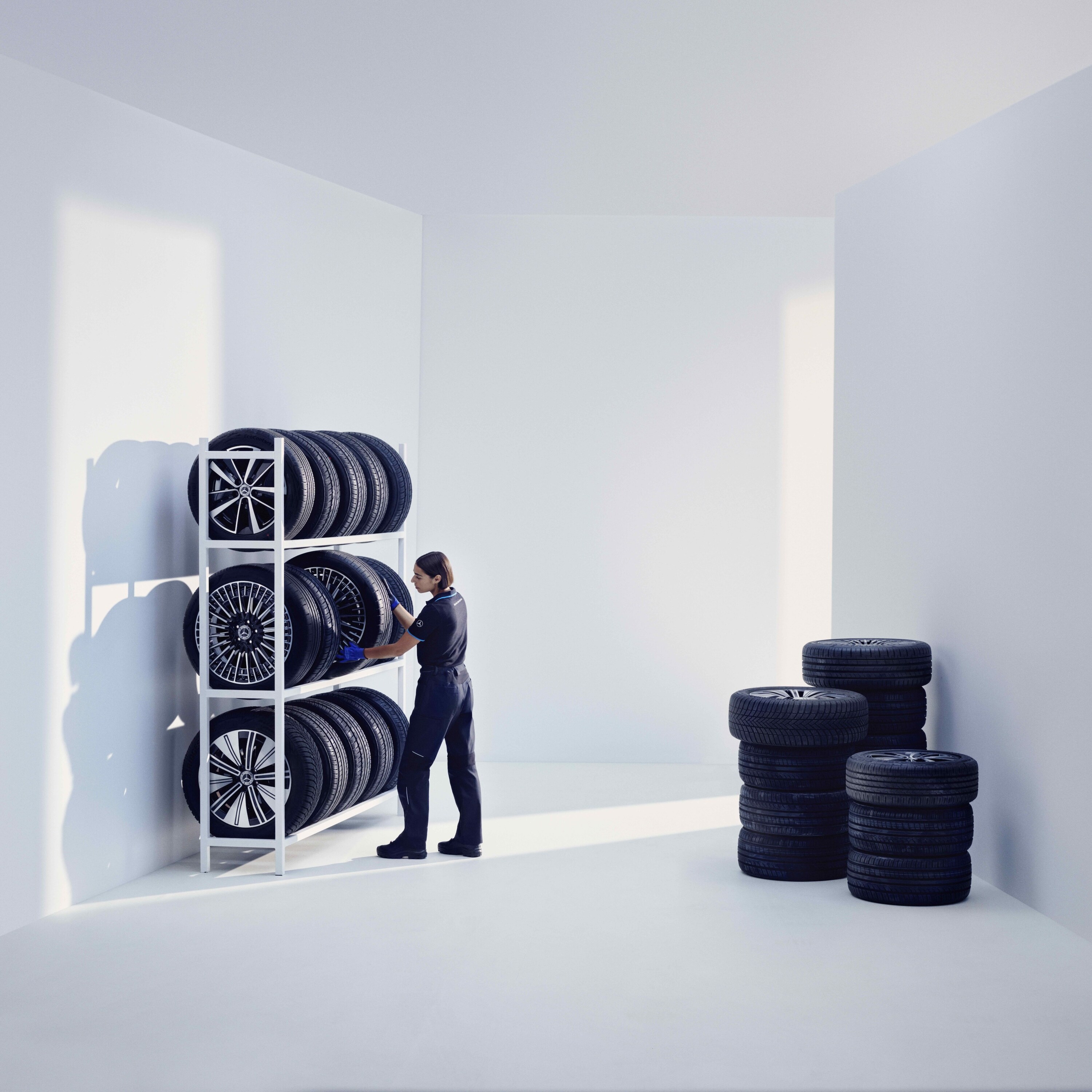 Un técnico de Mercedes-Benz guardando los neumáticos originales de Mercedes-Benz en una estantería.