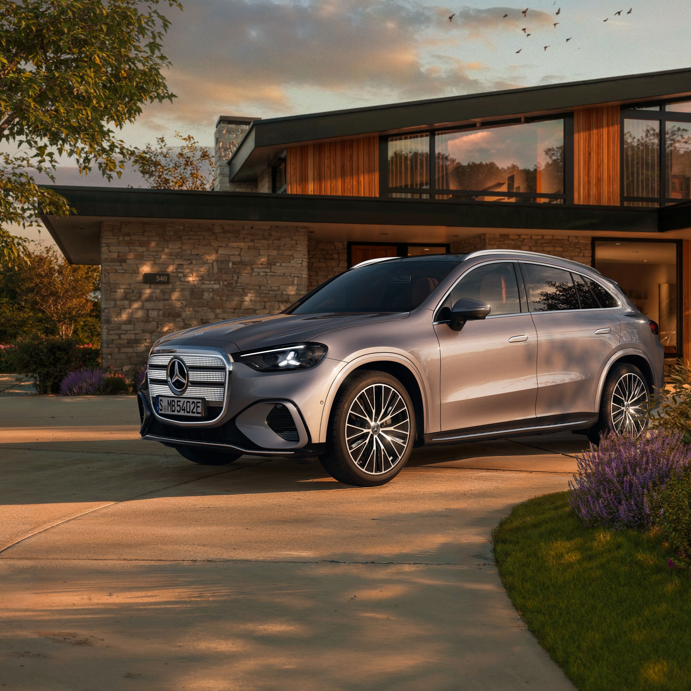 Visual de un GLC plateado de Mercedes-Benz aparcado al frente de una casa
