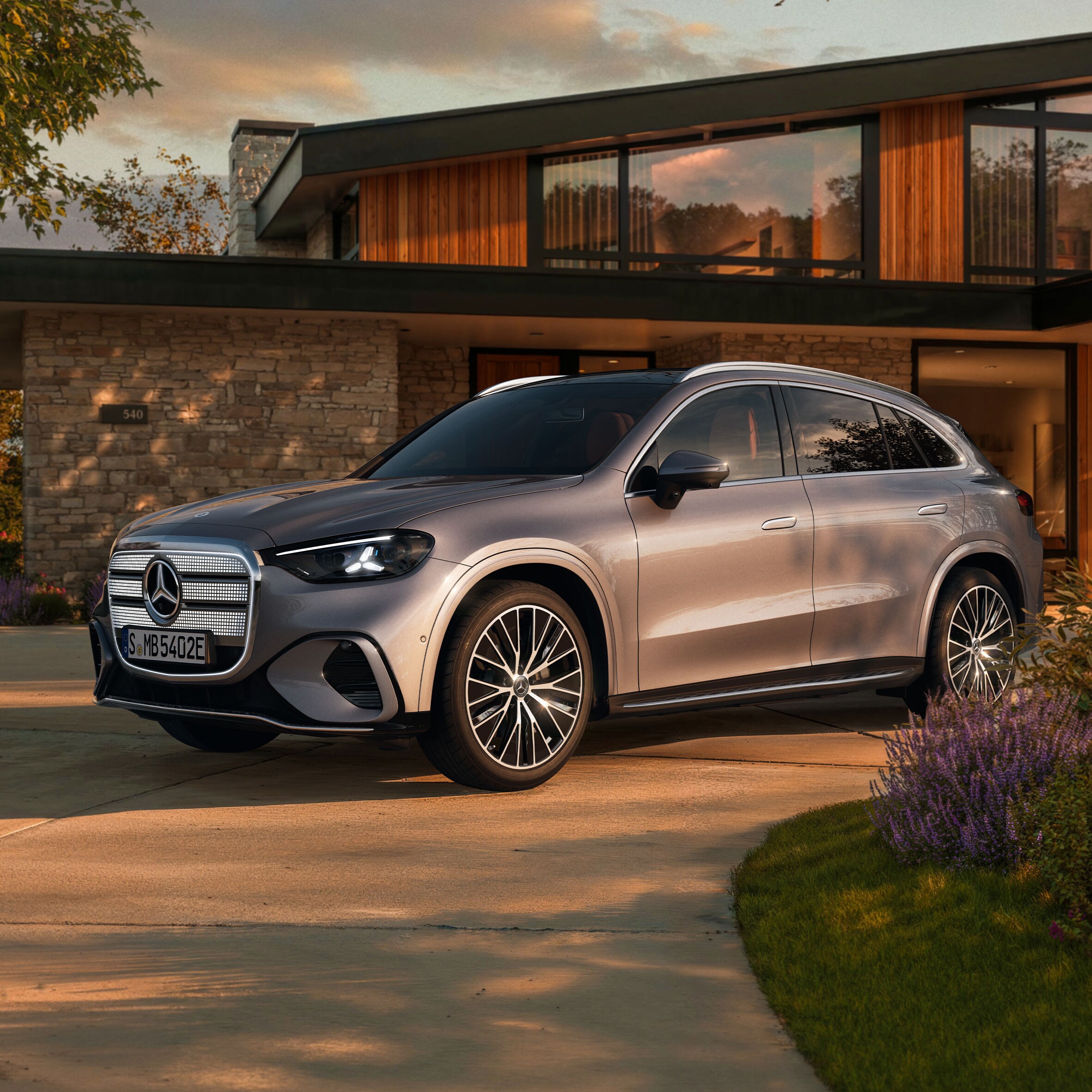 Visual del nuevo GLC eléctrico en color gris de Mercedes-Benz aparcado fuera de una casa