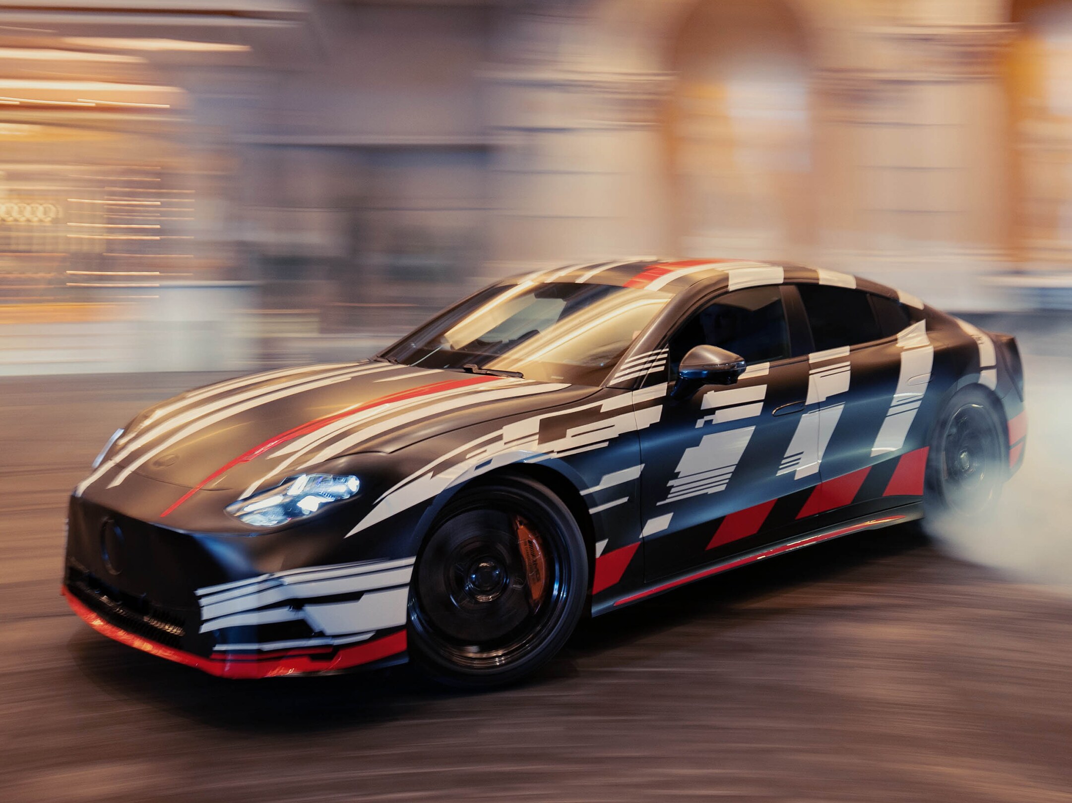 Visual lateral del nuevo Mercedes-AMG GT 4 Puertas Coupé en color negro con rayas blancas y rojas derrapanado en una pista