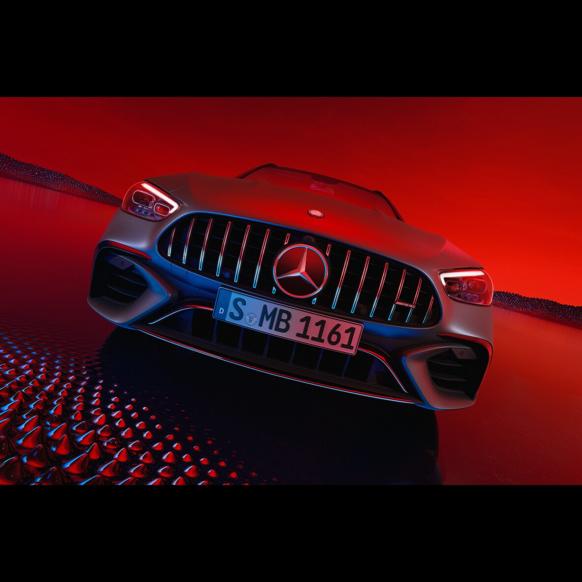 Vista de frente del Mercedes-AMG C 63 S E PERFORMANCE frente a un fondo rojo.