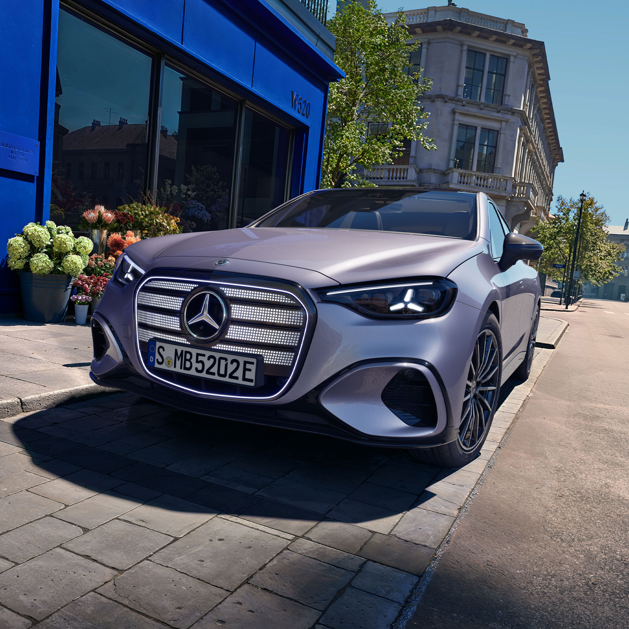 Visual lateral frontal del nuevo Clase C eléctrico en gris con la parrilla en gris de Mercedes-Benz aparcado frente de una casa