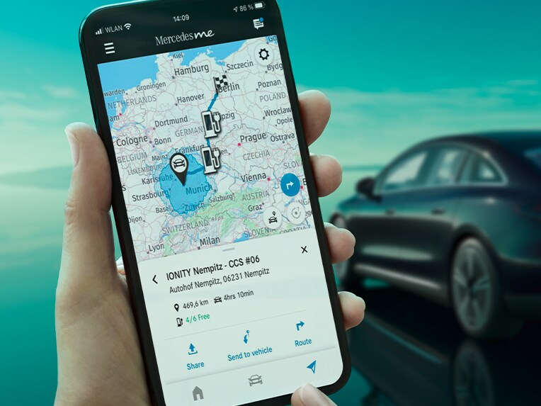 La aplicación Mercedes-Benz ECO Coach en un smartphone y, de fondo, el EQE berlina cargando en una Wallbox.