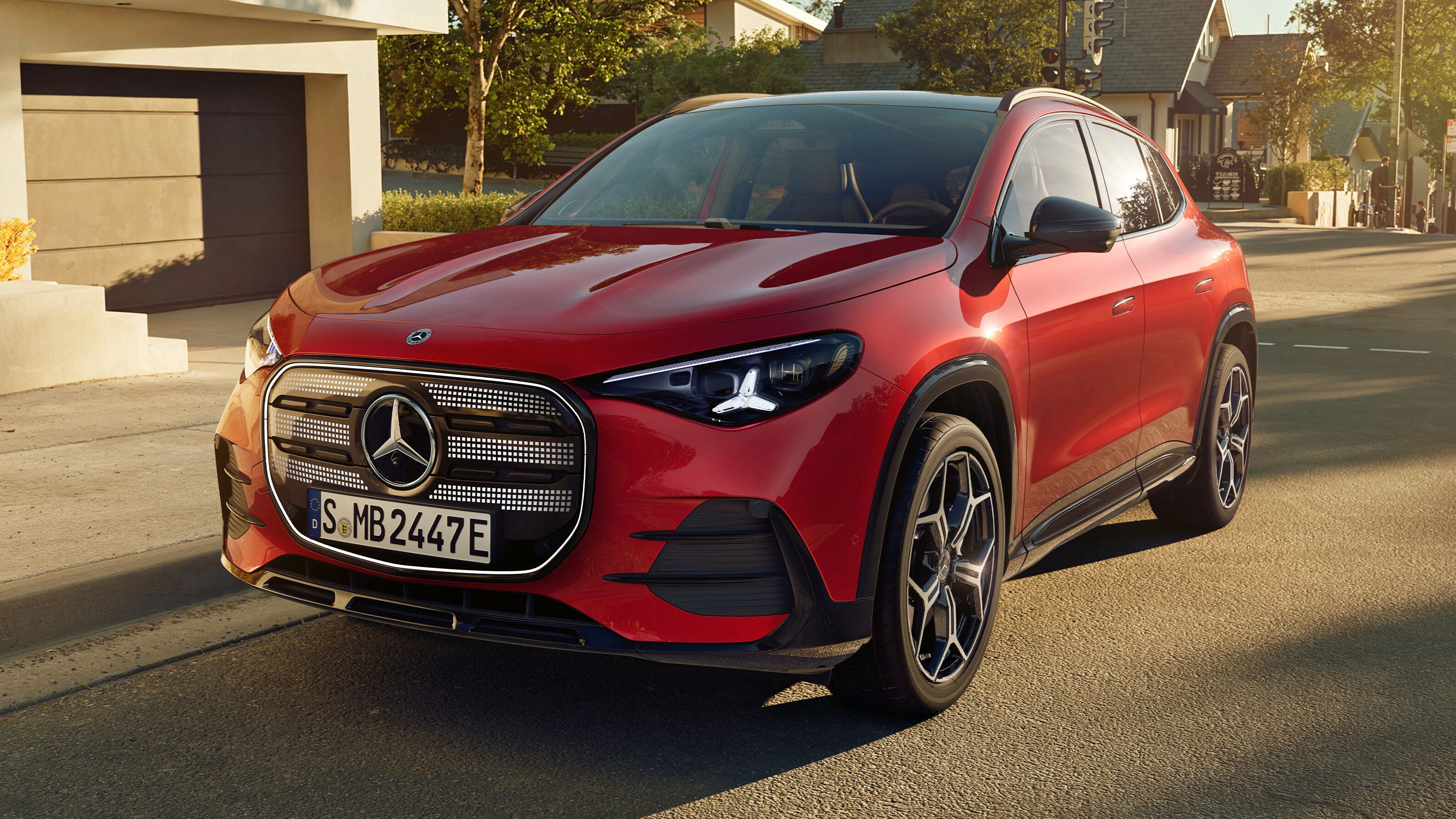 Visual lateral del nuevo GLA eléctrico en color rojo frente a una casa