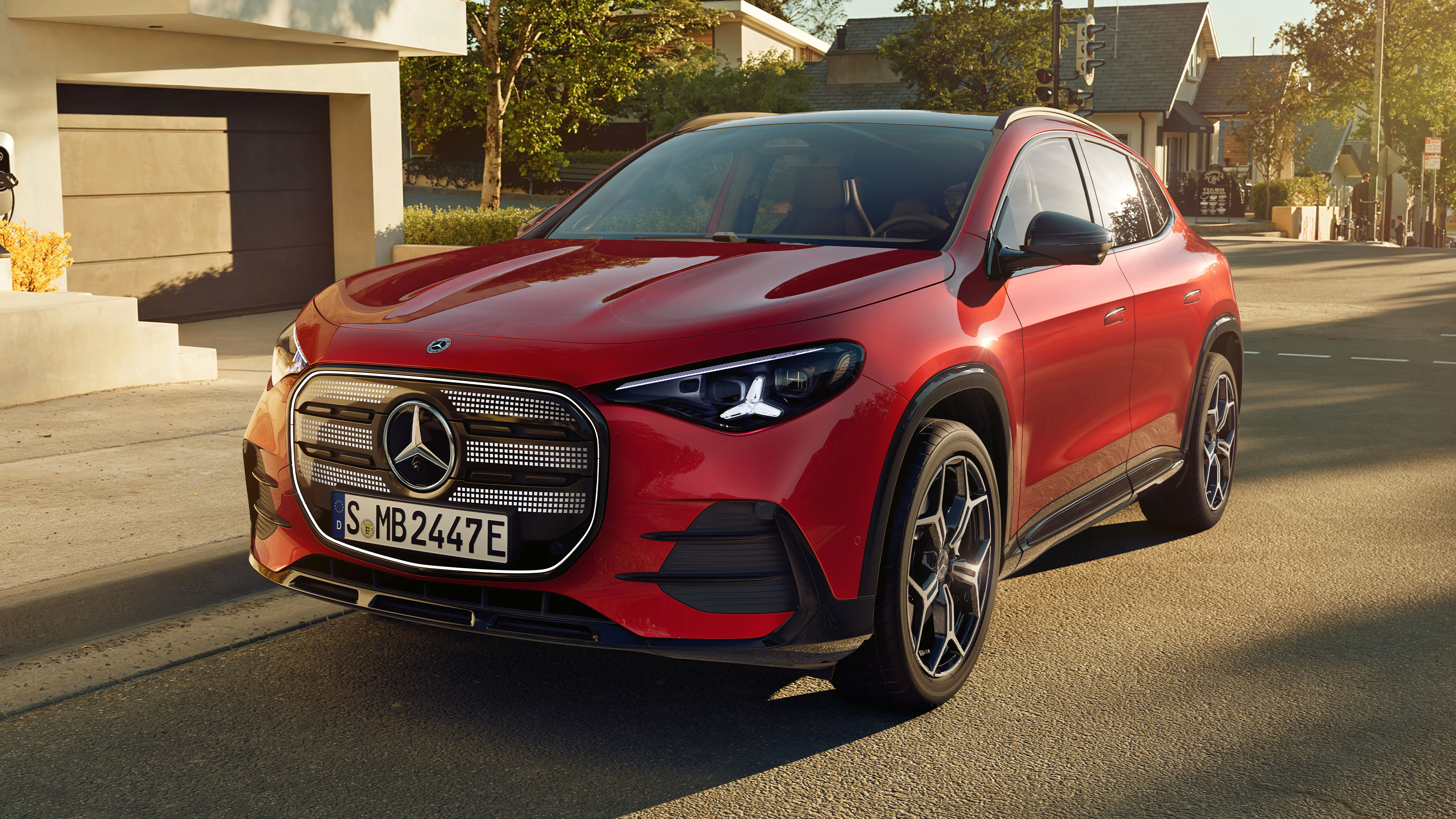 Visual lateral del nuevo GLA eléctrico en color rojo frente a una casa
