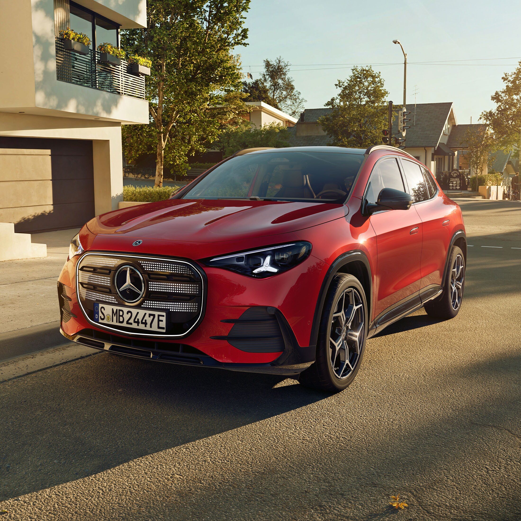 Visual lateral del nuevo GLA eléctrico en color rojo frente a una casa