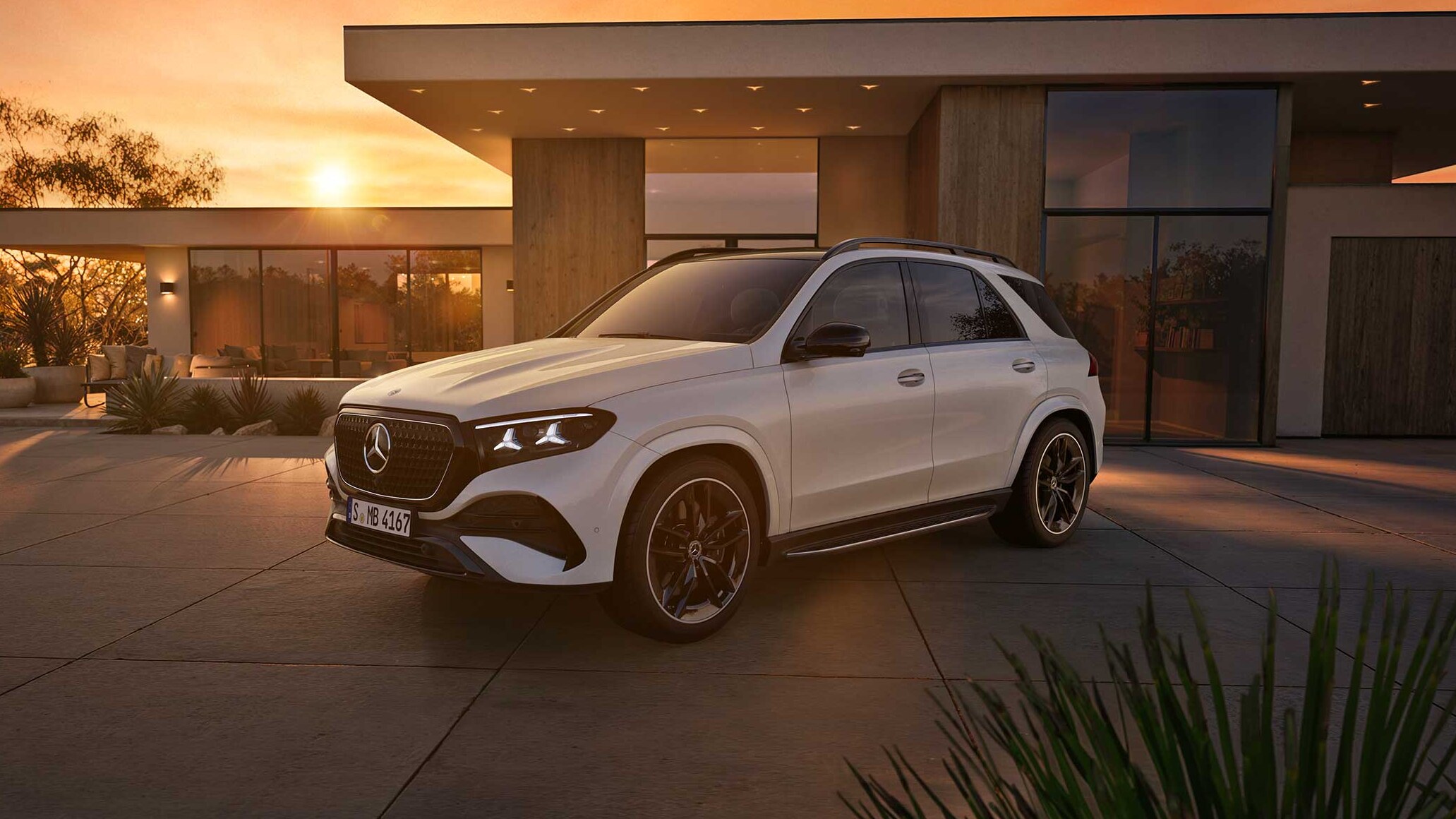 Visual lateral del nuevo GLE en color blanco aparcado enfrente de una casa con el amanecer de fondo