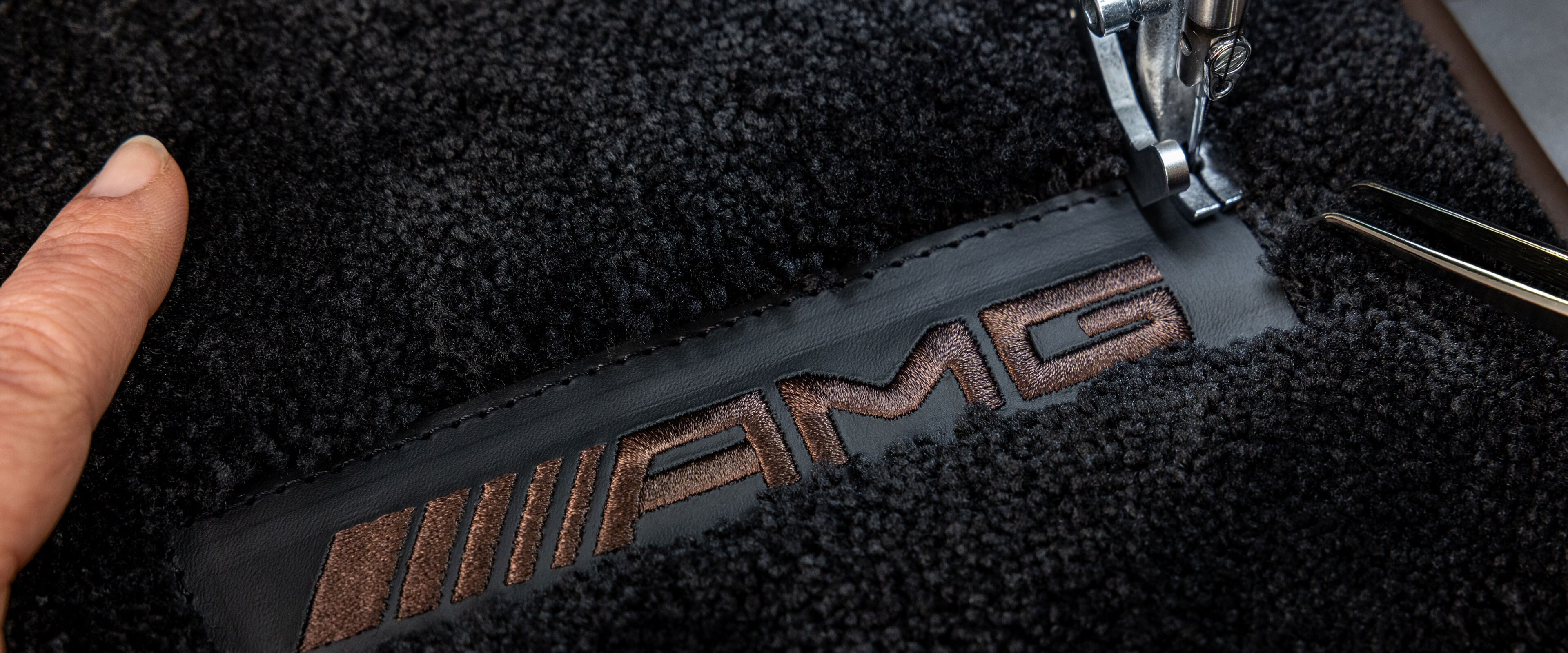 Inscripción MANUFAKTUR sobre una superficie oscura en un Mercedes-AMG.