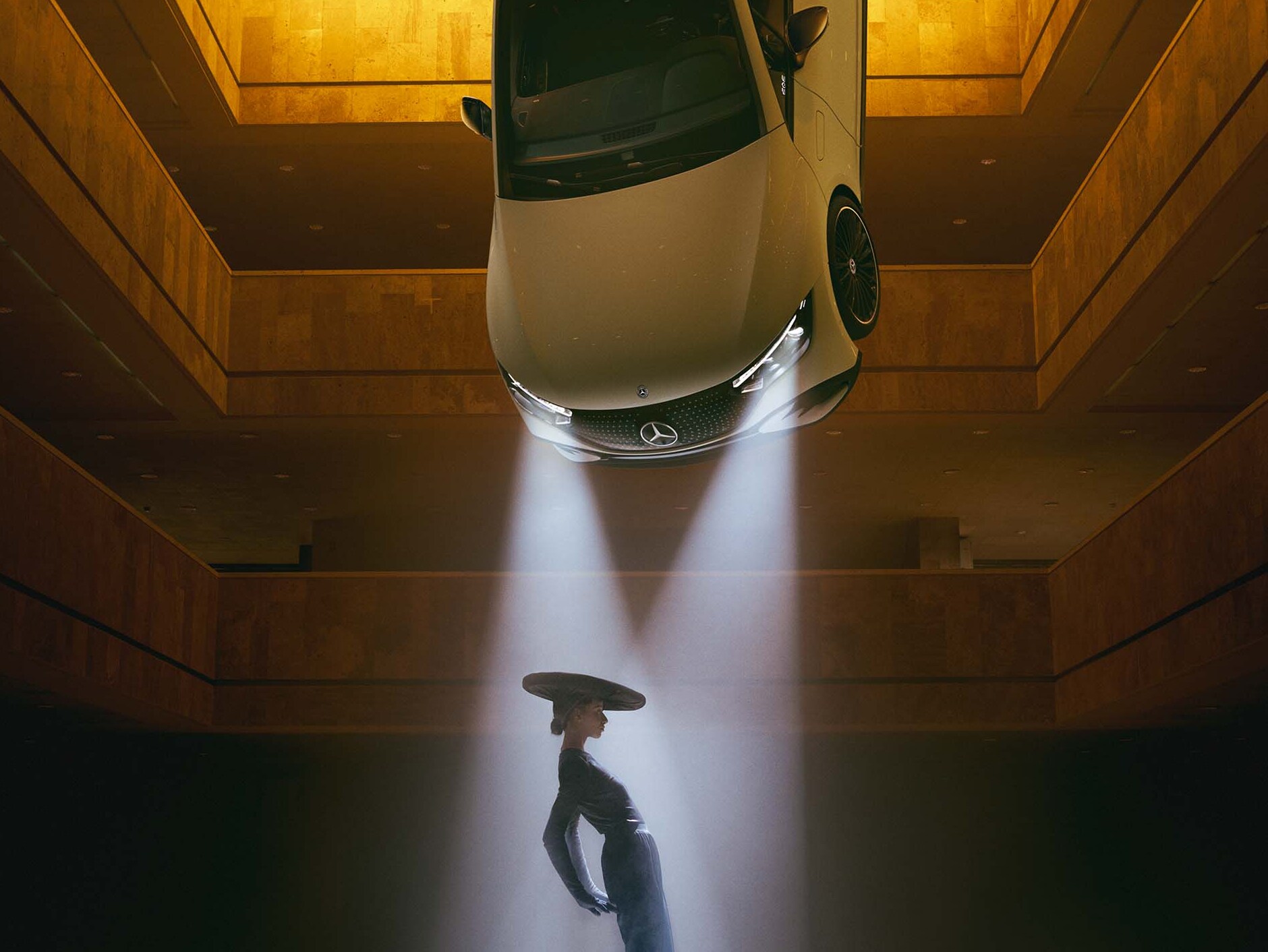 Una sala oscura con faros en el techo, en cuyo cono luminoso se encuentra una mujer.