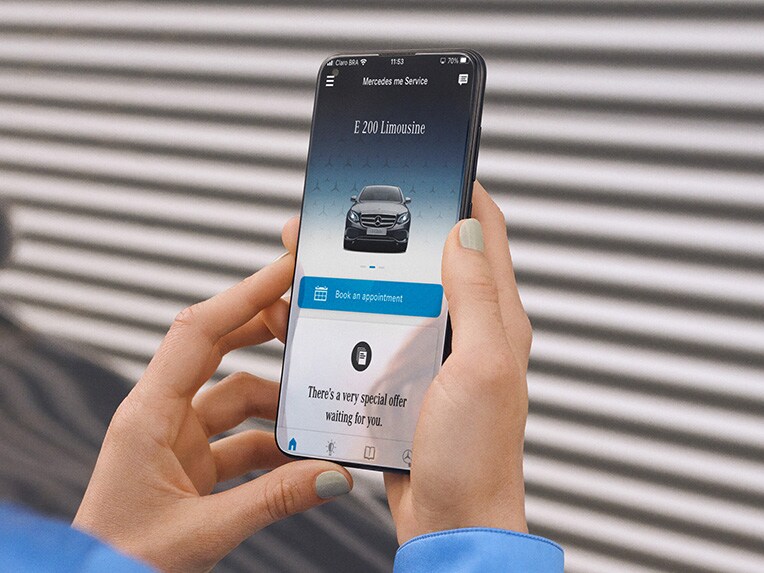 Un smartphone y un primer plano de los faros de un vehículo Mercedes-Benz.