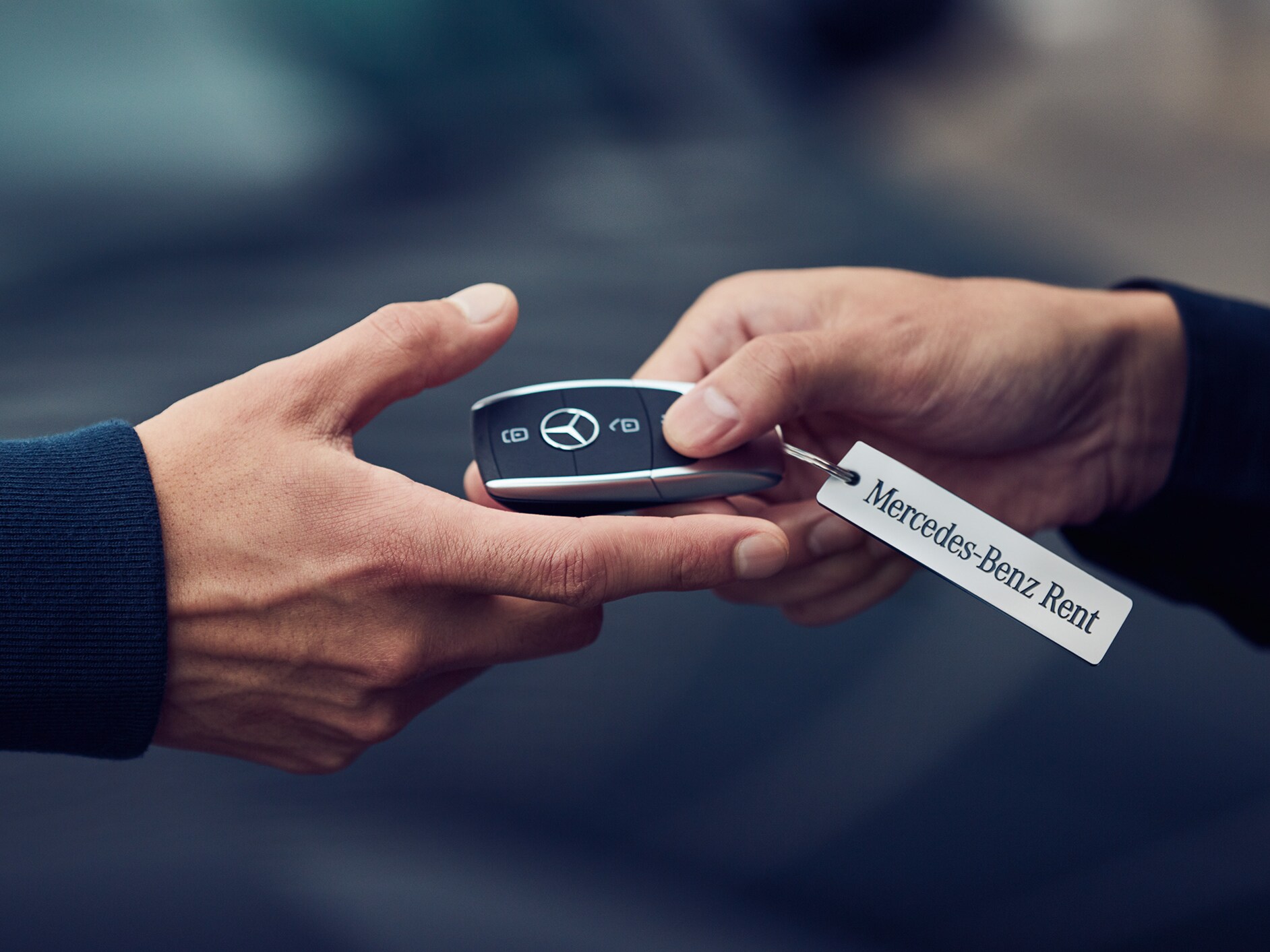 Dos manos en el momento de entrega de una llave Mercedes-Benz.