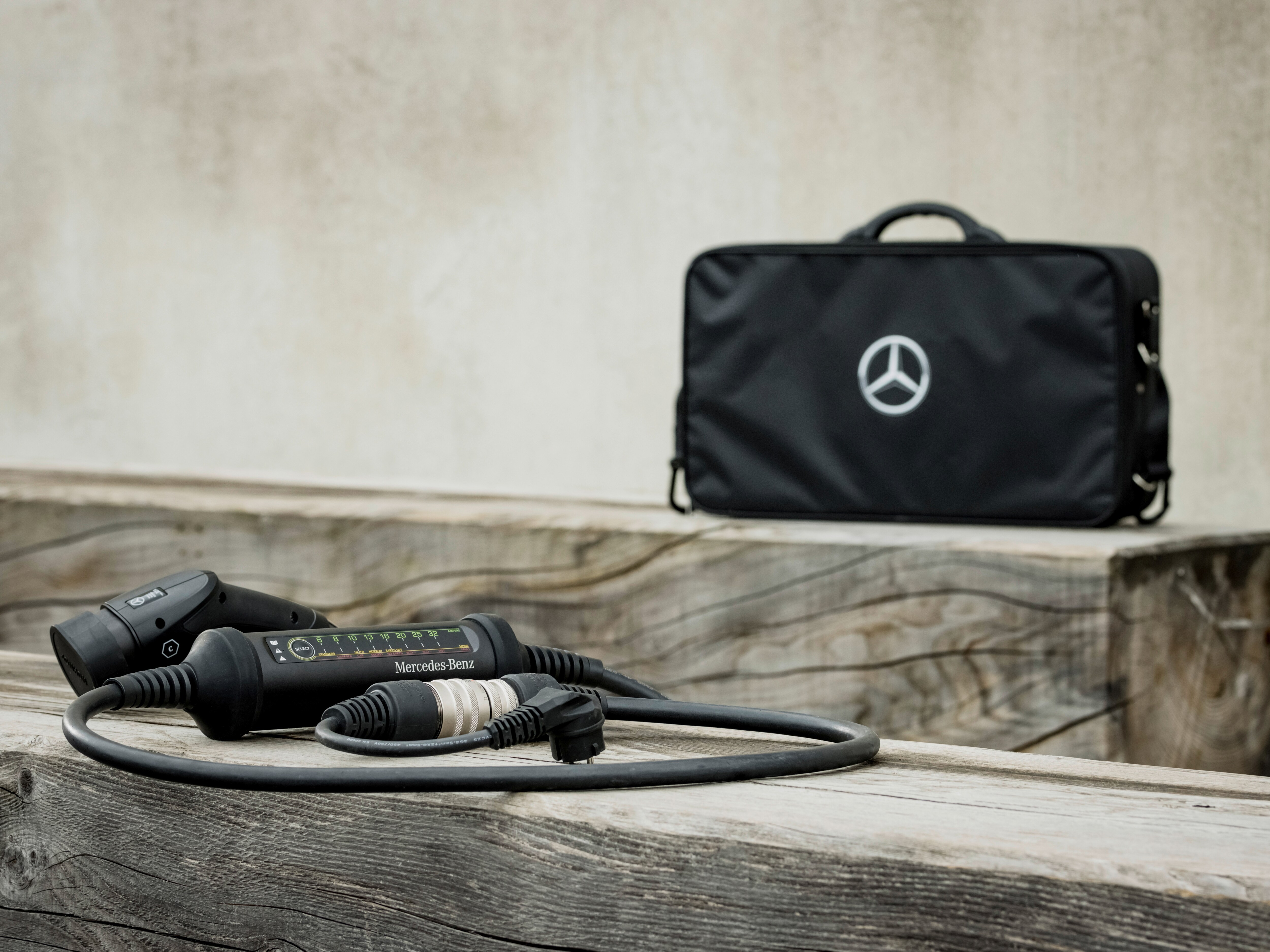 Una bolsa negra con la estrella Mercedes sobre una viga de madera, delante de la cual hay varios conectores macho del vehículo
