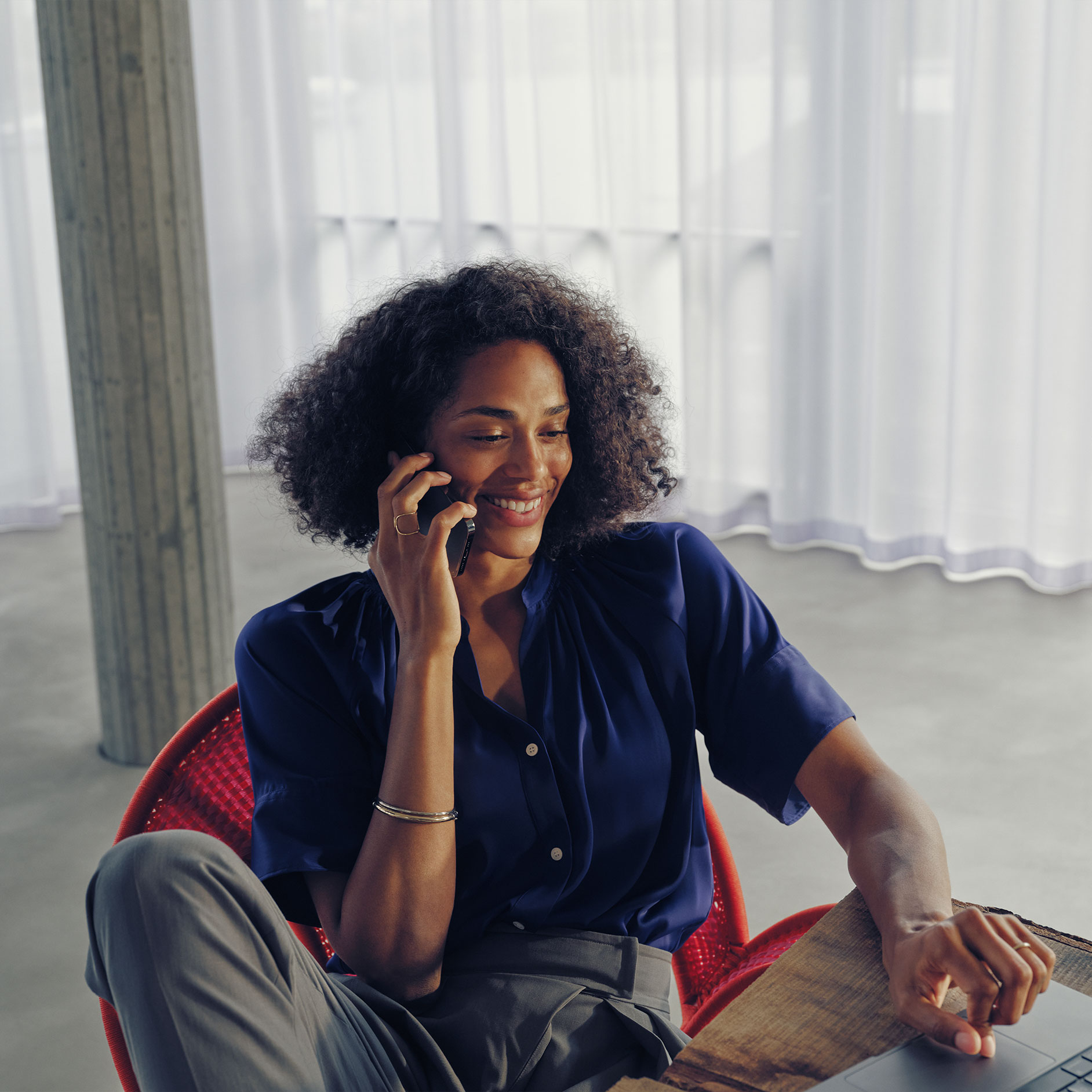 Preguntas | Carga | Mercedes-Benz Una mujer sentada en una mesa hablando por teléfono.