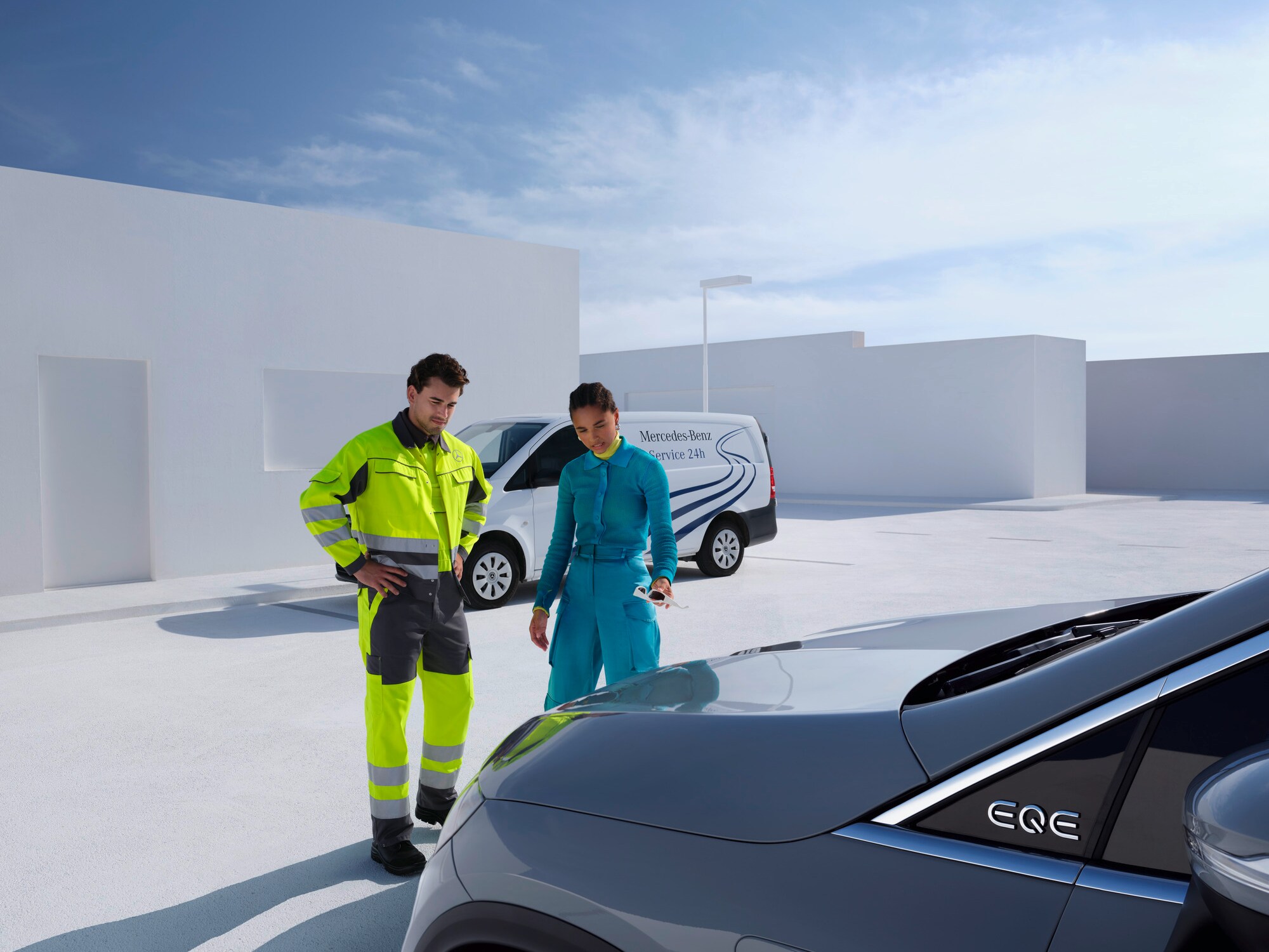 Integrante de un equipo de asistencia de Mercedes-Benz Service24 consultando con un cliente delante de un vehículo Mercedes-Benz.