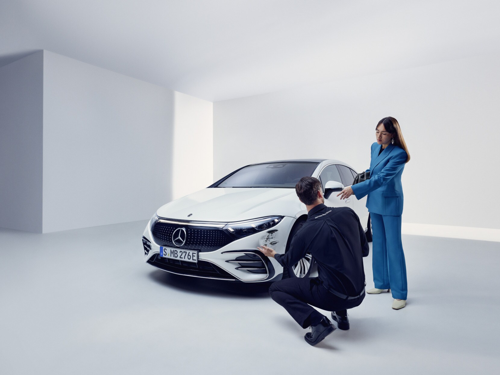 Un integrante del equipo de asistencia de Mercedes-Benz arrodillado junto a un Mercedes-Benz averiado.