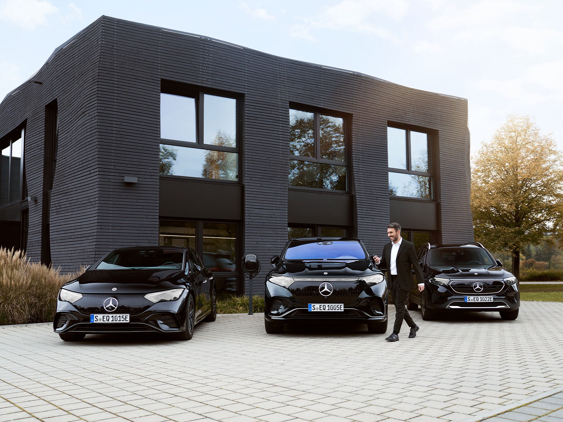 Tres Mercedes-Benz eléctricos delante de un edificio de oficinas.
