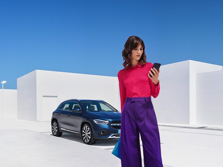 Una mujer utiliza el smartphone para conectarse con su Mercedes-Benz a través de la Mercedes-Benz Service App.