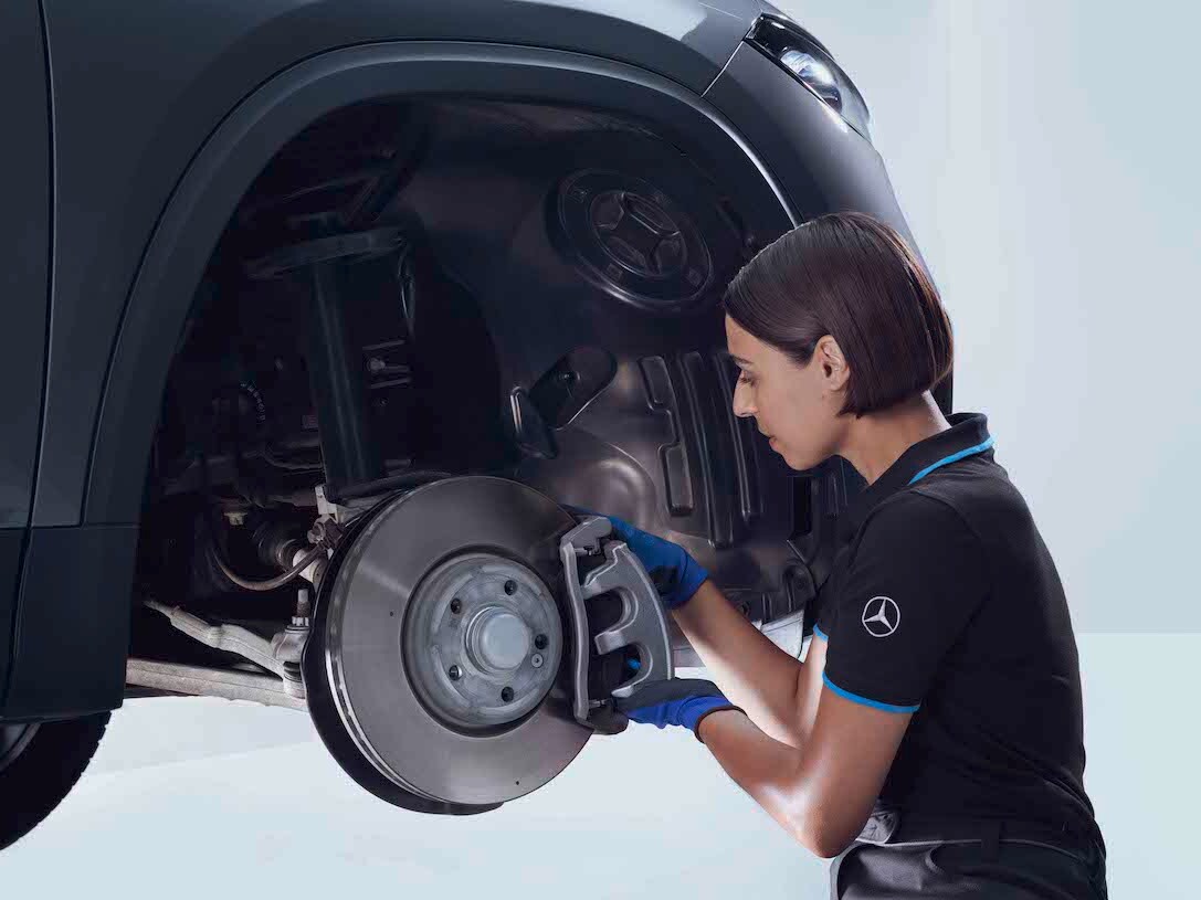 Una mujer revisando los frenos de un Mercedes-Benz
