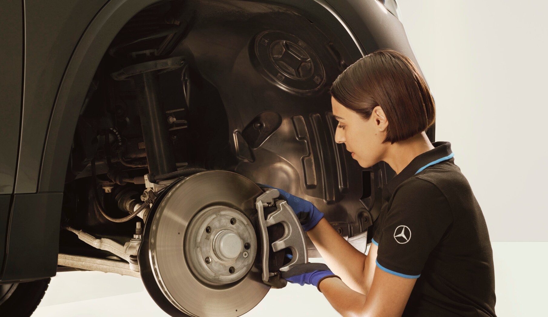 Un técnico reparando los frenos de un vehículo Mercedes-Benz.