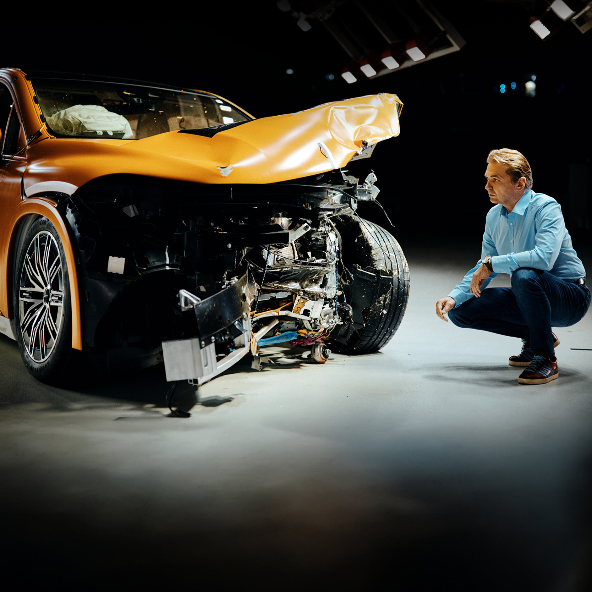 Expertos en pruebas de choque | Seguridad | Mercedes-Benz Un experto en pruebas de choque agachado junto a un Mercedes-Benz, examinándolo luego de un impacto frontal.
