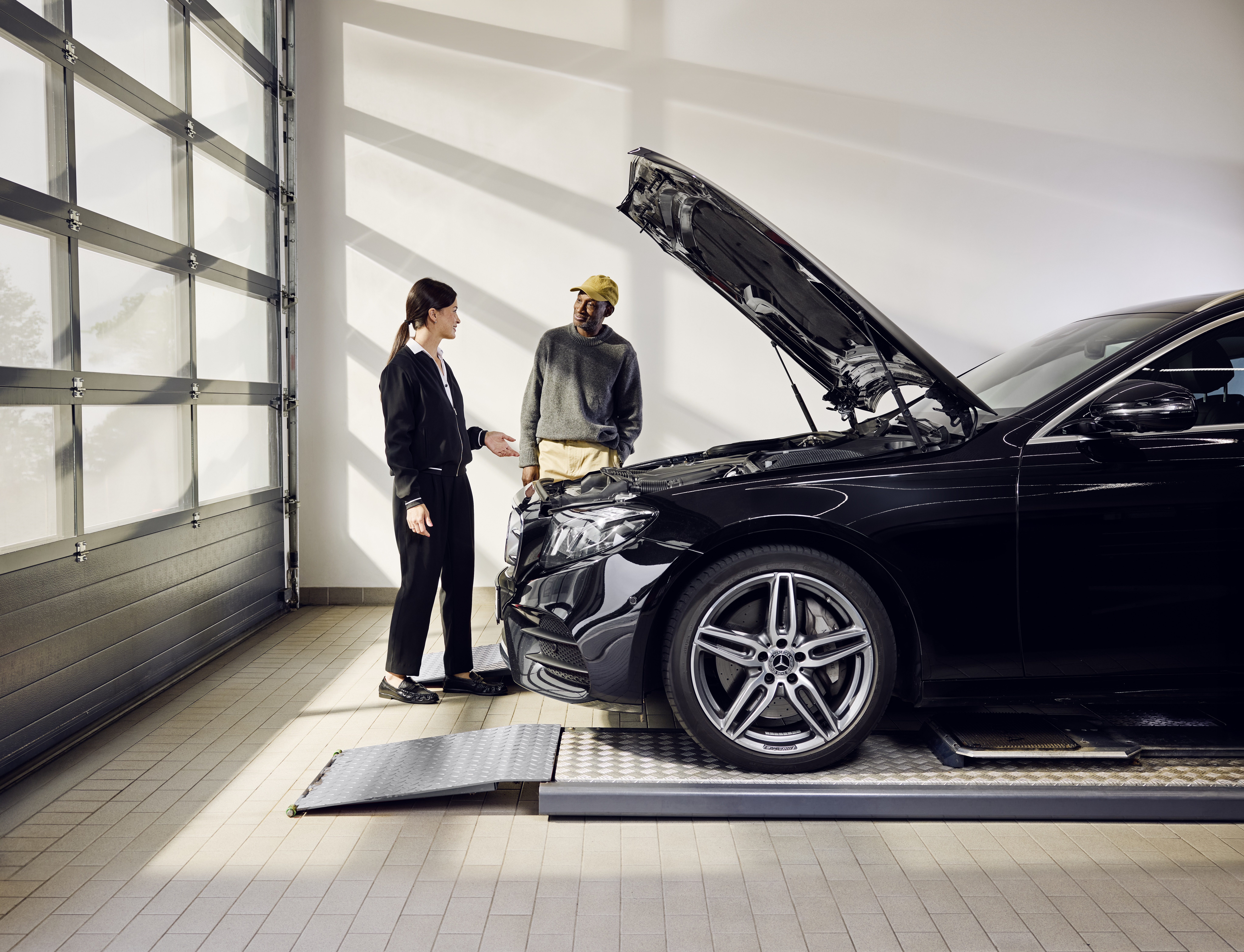 Recambio de piezas originales Mercedes-Benz Vehículo Mercedes-Benz posicionado en una rampa de servicio con el capó abierto durante un cambio profesional de piezas originales en un punto de servicio.