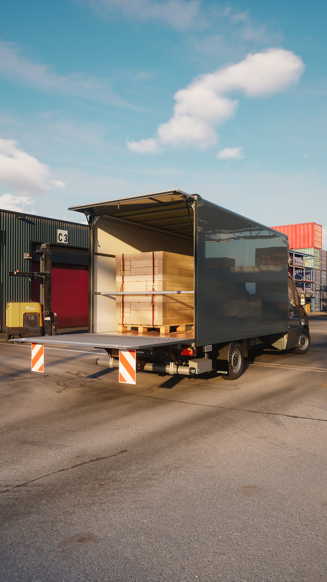 Mercedes-Benz Sprinter con carrocería de caja cerrada para carga seca de Junge durante la carga en un centro logístico: solución de transporte eficiente para carga general y manipulación de mercancías. La puerta trasera abierta muestra paneles de madera paletizados en la zona de carga durante la carga o descarga.