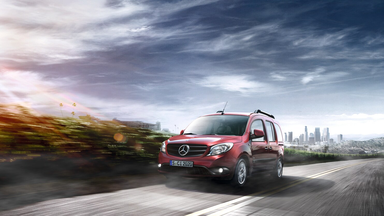 Mercedes-Benz Citan rojo transitando por una carretera con vistas panorámicas con el horizonte de la ciudad de fondo