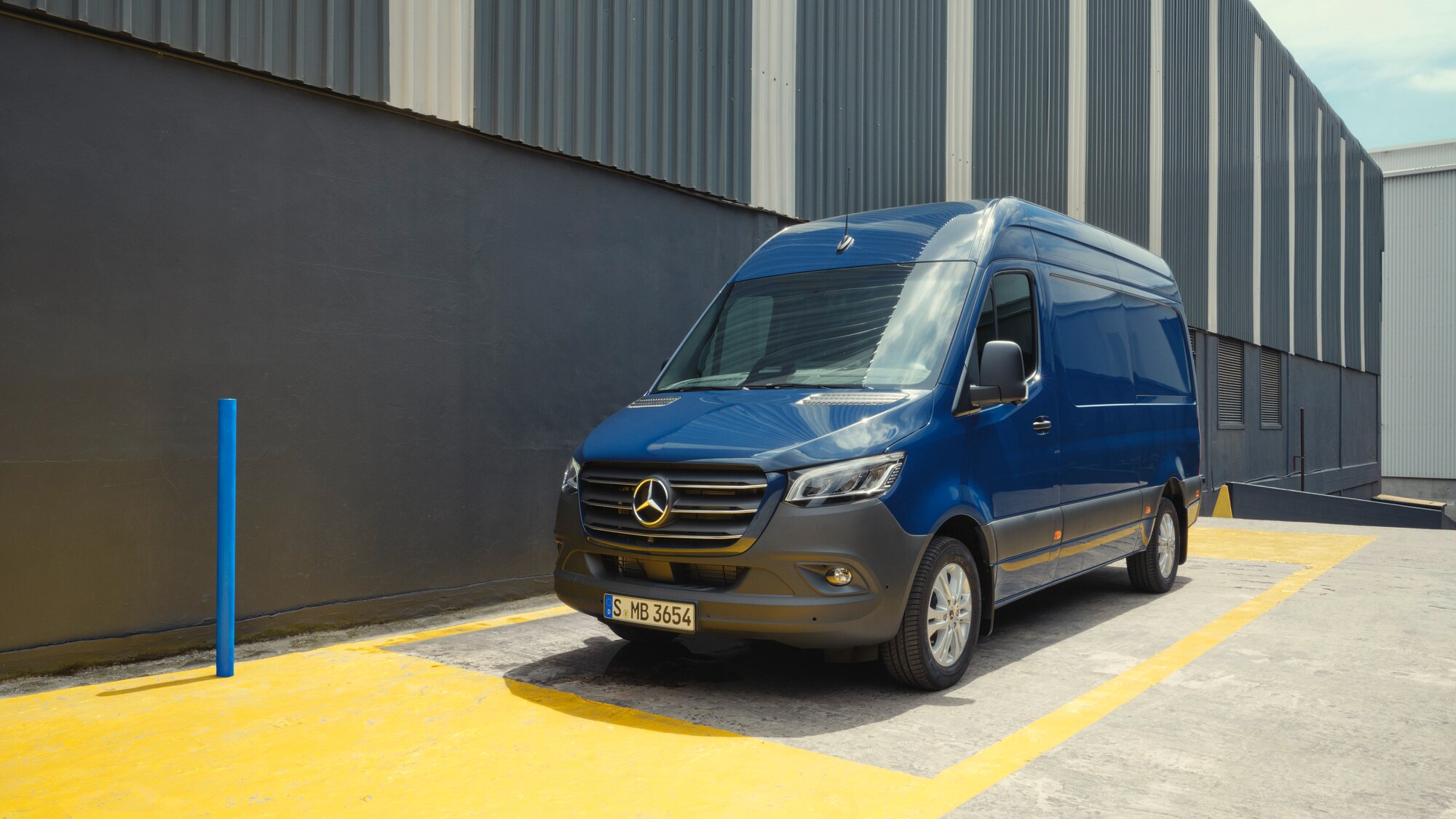 Furgoneta Mercedes-Benz Sprinter azul aparcado junto a un edificio industrial