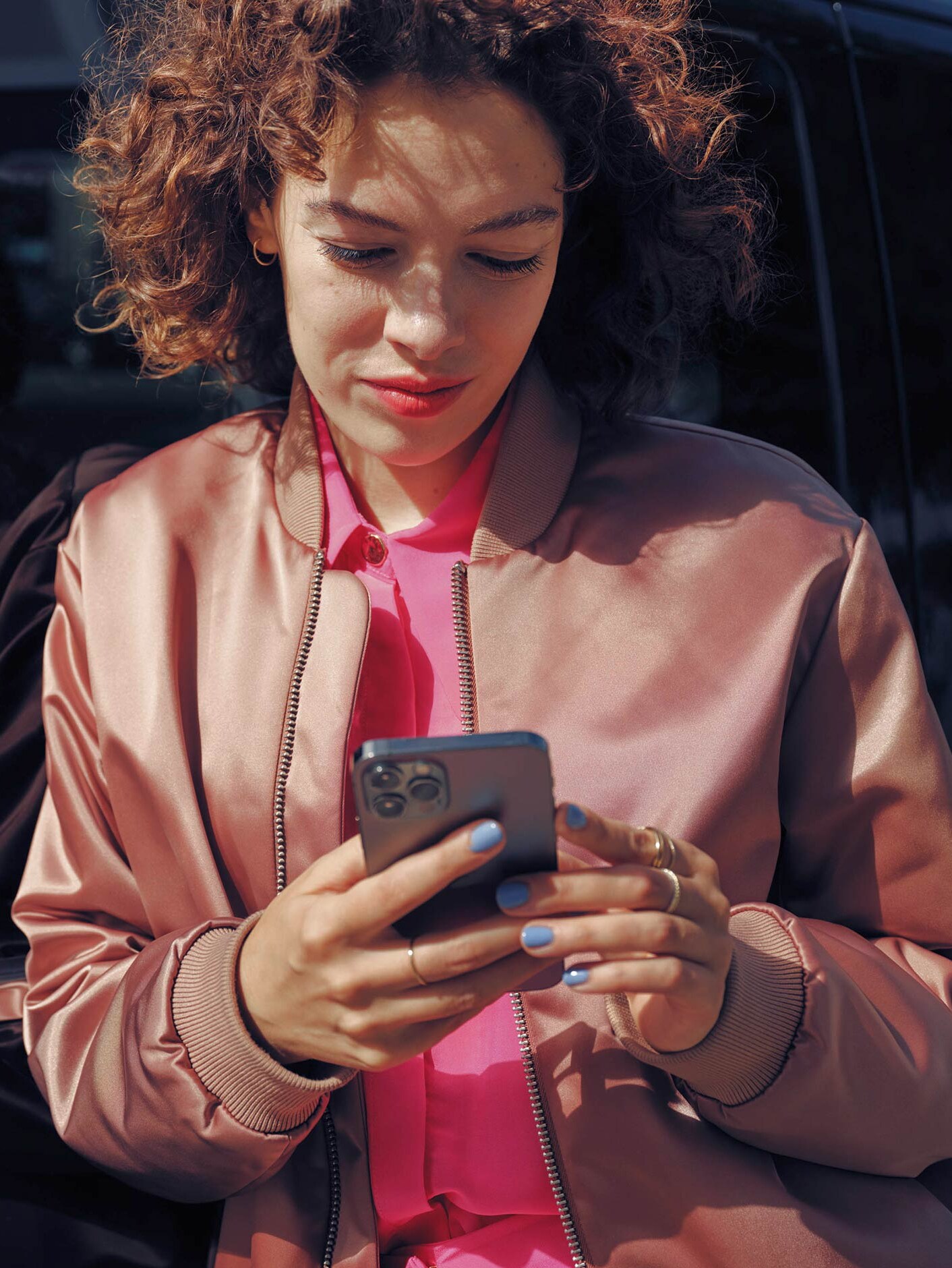 Mujer hablando por teléfono móvil junto al monovolumen EQV negro de Mercedes-Benz