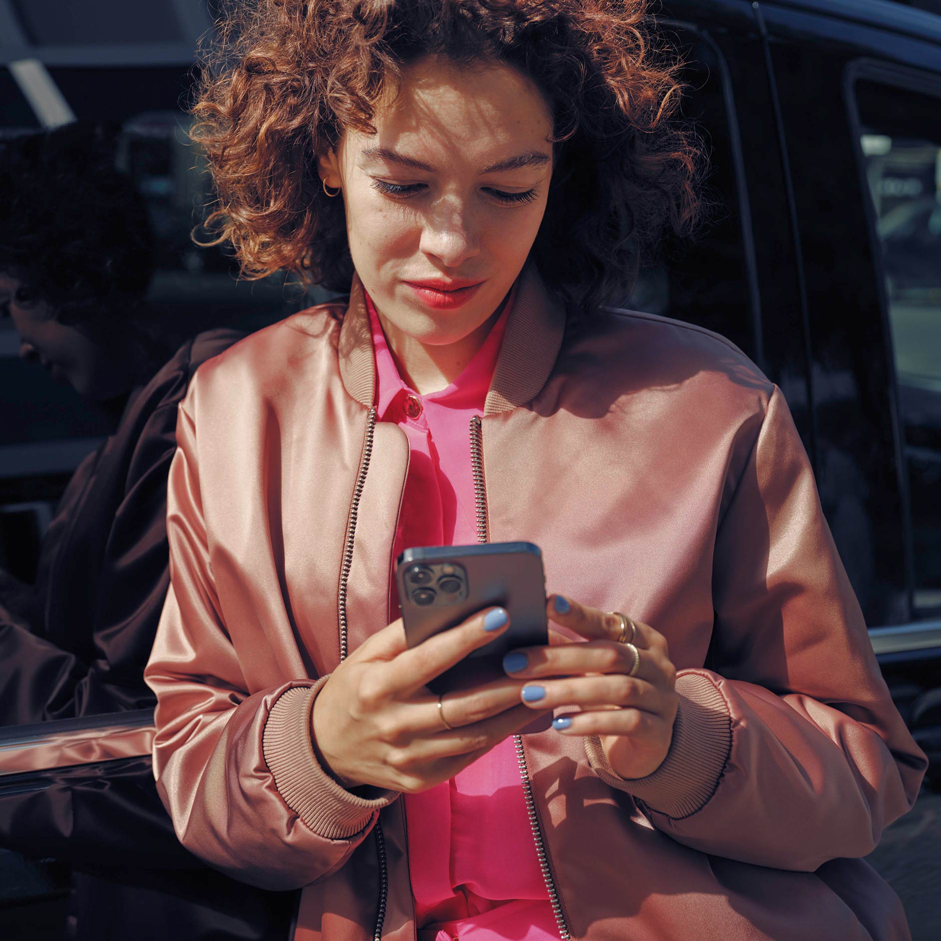 Alquiler | Servicios financieros | Furgonetas Mercedes-Benz Mujer hablando por teléfono móvil junto al monovolumen EQV negro de Mercedes-Benz