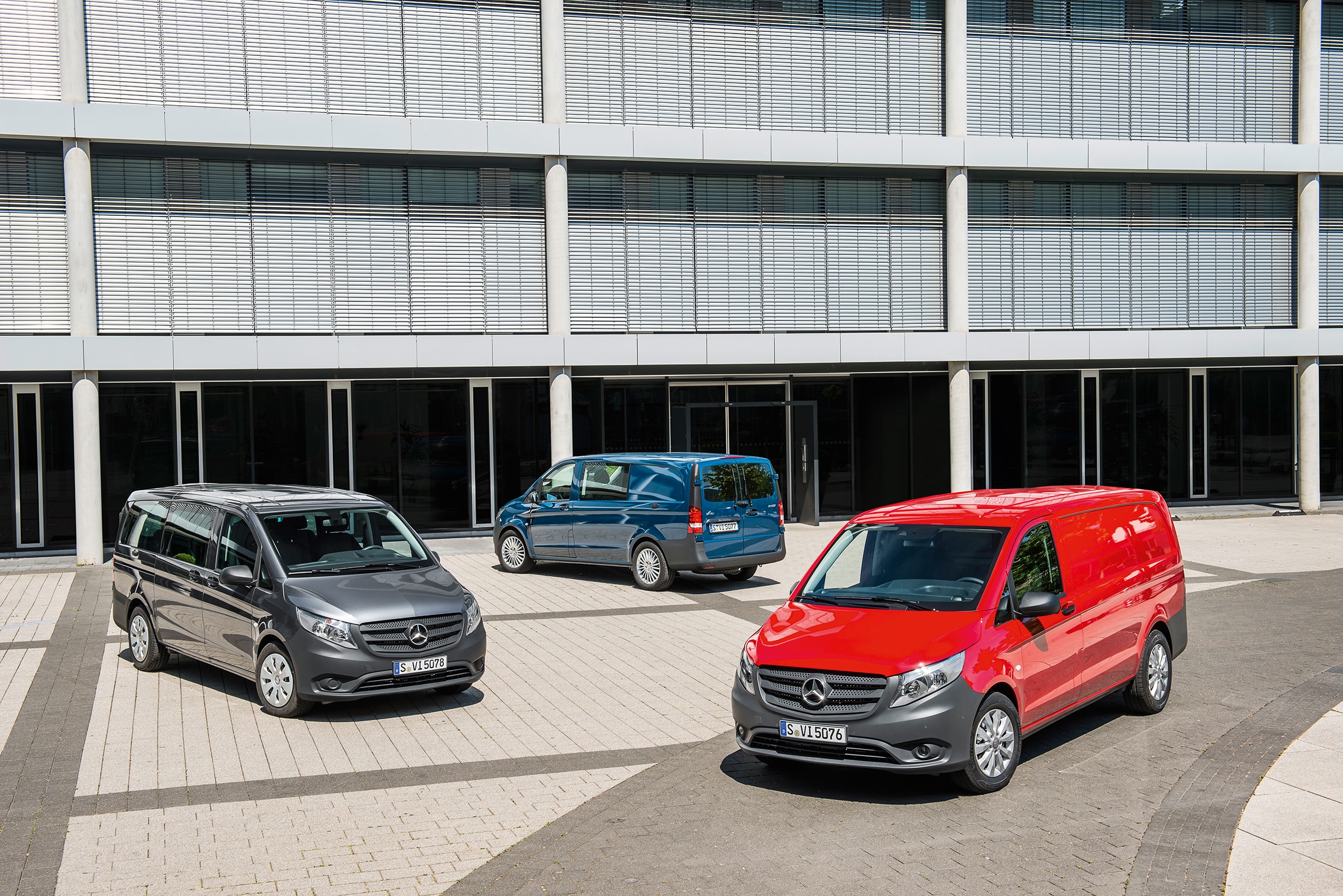 La tercera generación del Mercedes-Benz Vito | Historia de los vehículos industriales | Mercedes-Benz Varias furgonetas Mercedes-Benz Vito aparcadas frente a un moderno edificio de oficinas