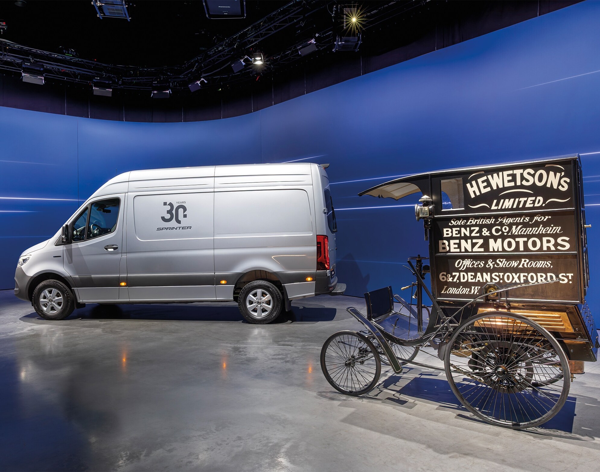 Una furgoneta Mercedes-Benz Sprinter y un histórico vehículo de reparto de Benz expuestos en una moderna sala de exposición