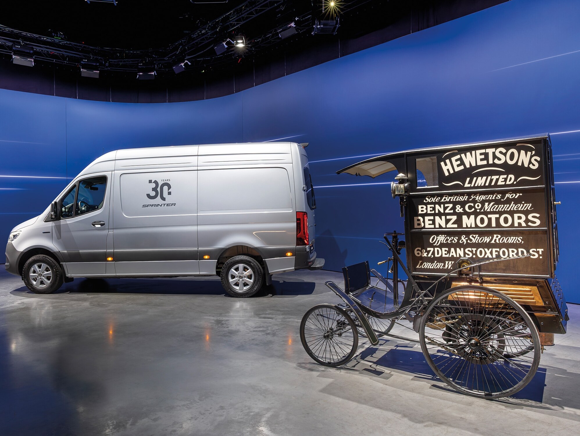 Una furgoneta Mercedes-Benz Sprinter y un histórico vehículo de reparto de Benz expuestos en una moderna sala de exposición