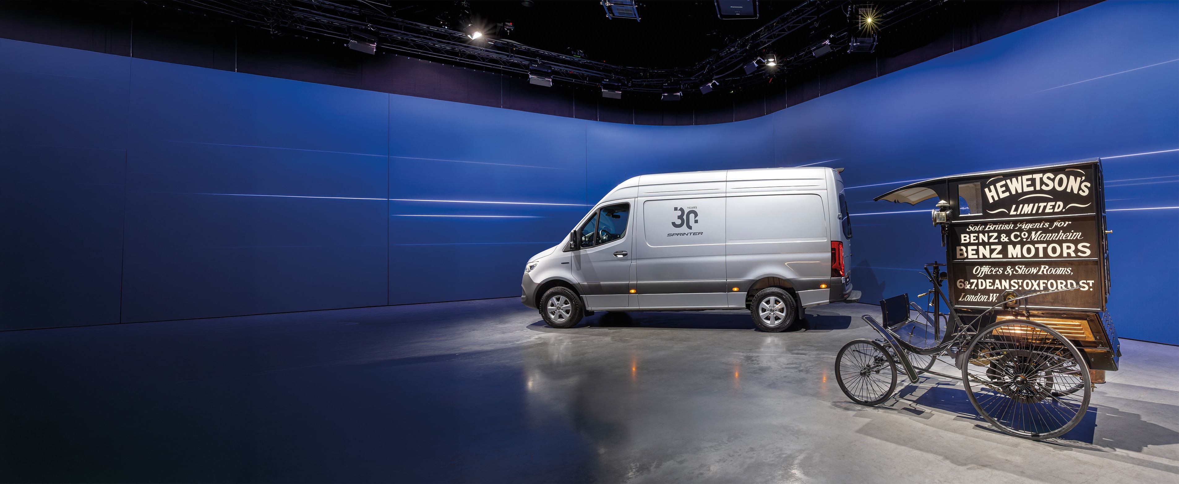Historia | Vehículos industriales | Mercedes-Benz Una furgoneta Mercedes-Benz Sprinter y un histórico vehículo de reparto de Benz expuestos en una moderna sala de exposición