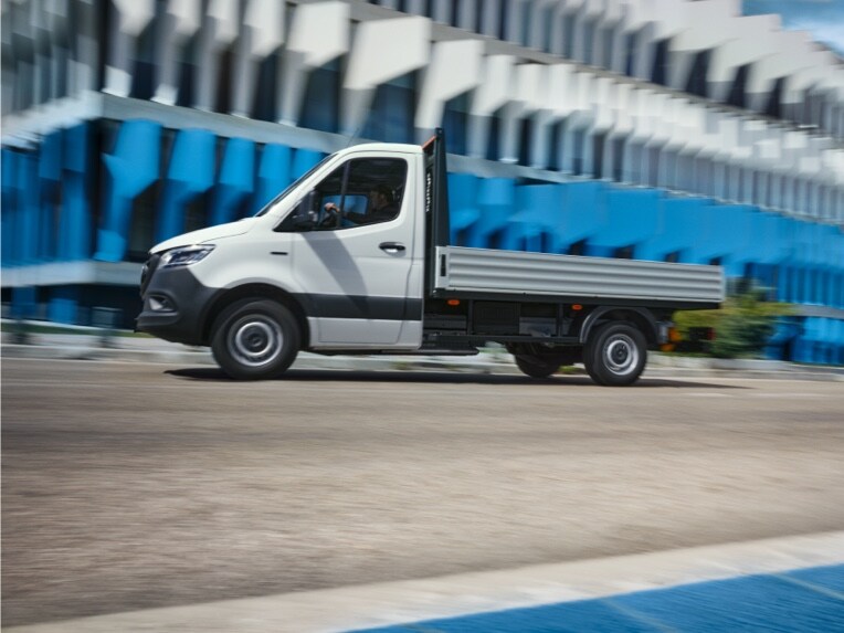 La eSprinter Chasis de Mercedes-Benz como vehículo de plataforma conduciendo delante de un edificio.