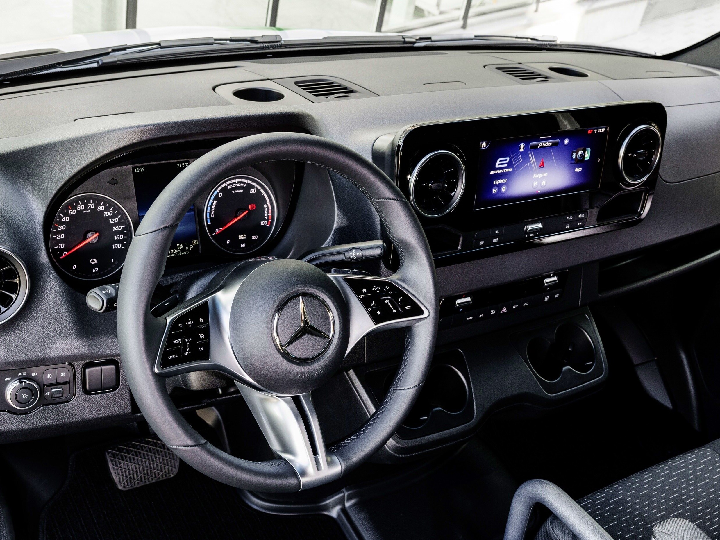 Puesto de conducción de la Mercedes-Benz con volante multifunción, cuadro de instrumentos analógico y pantalla multimedia, destacando la conectividad y la ergonomía para el conductor.