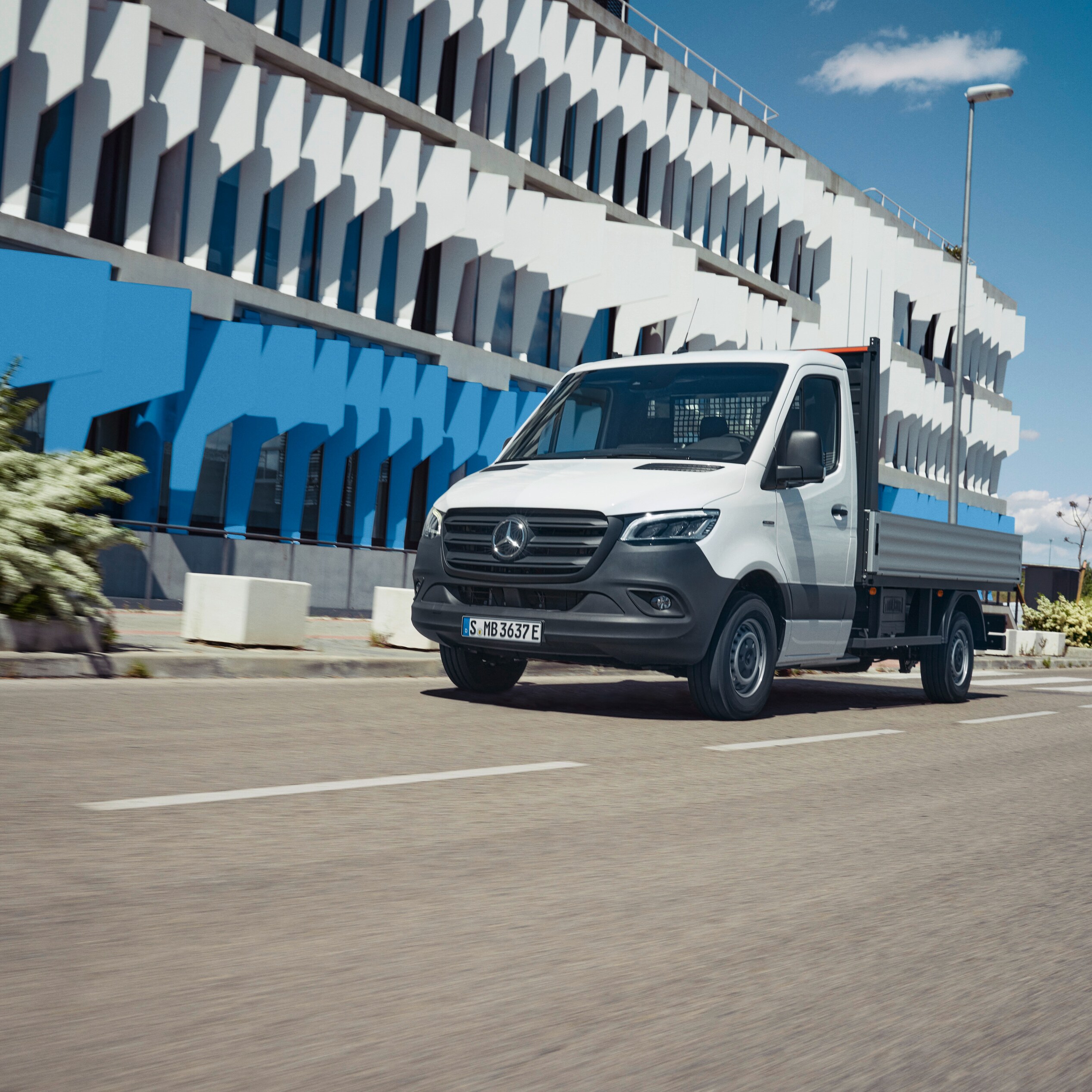 La eSprinter con caja abierta de Mercedes-Benz en movimiento por la ciudad.