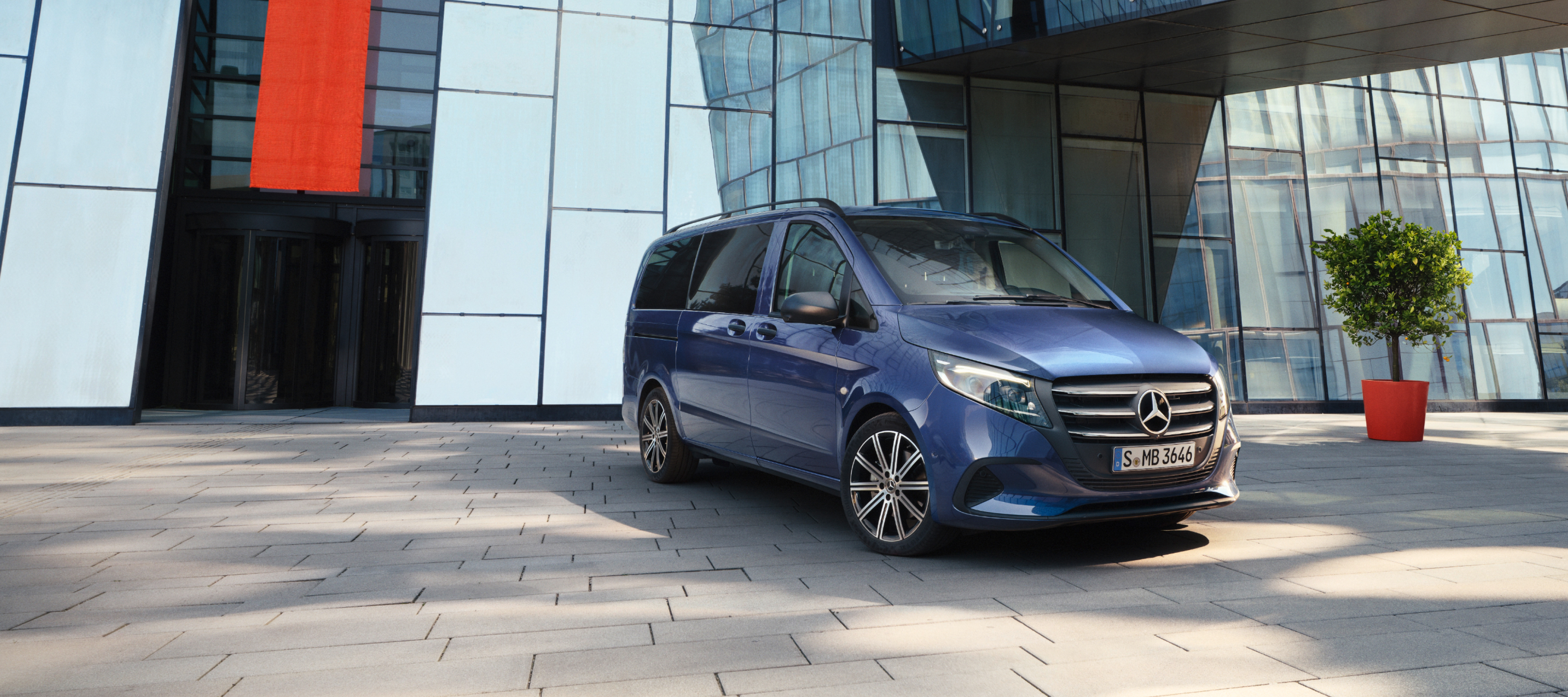 Comparación de vehículos | Vito Tourer | Mercedes-Benz Mercedes-Benz Vito Tourer delante de un edificio de oficinas.