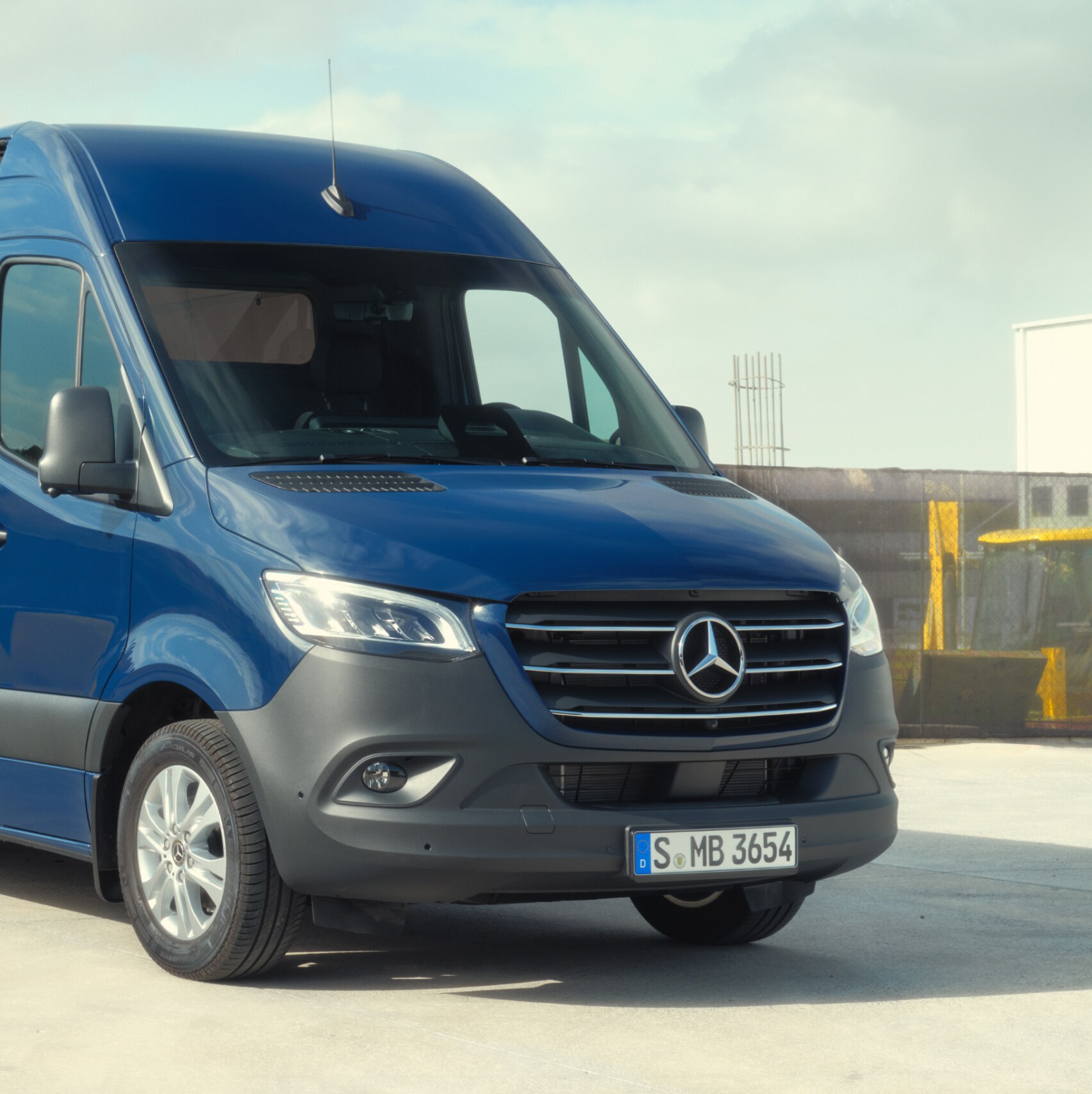 Furgón Mercedes-Benz Sprinter delante de materiales de construcción.