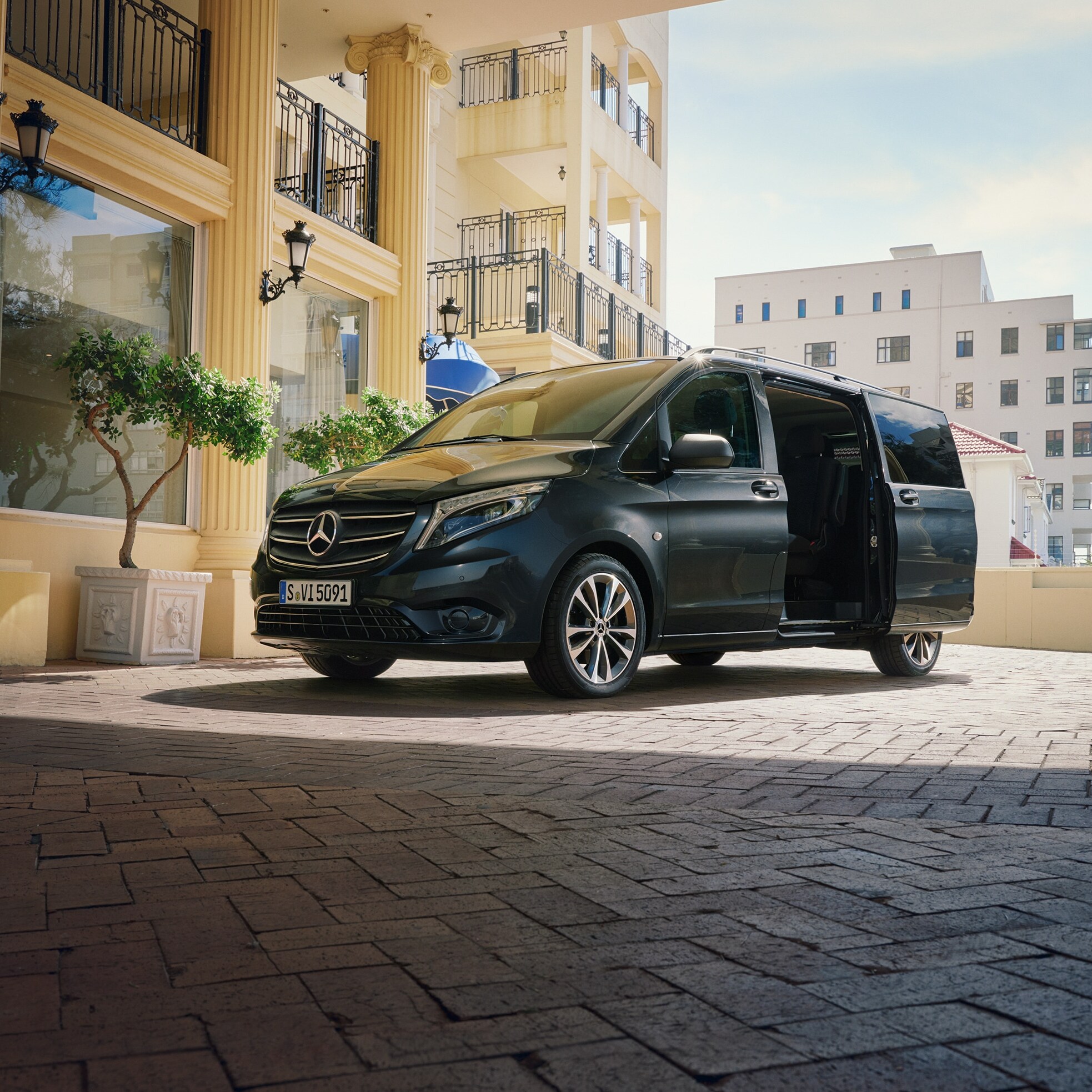 Una Mercedes‑Benz Vito Tourer aparcado a la entrada de un edificio lujoso