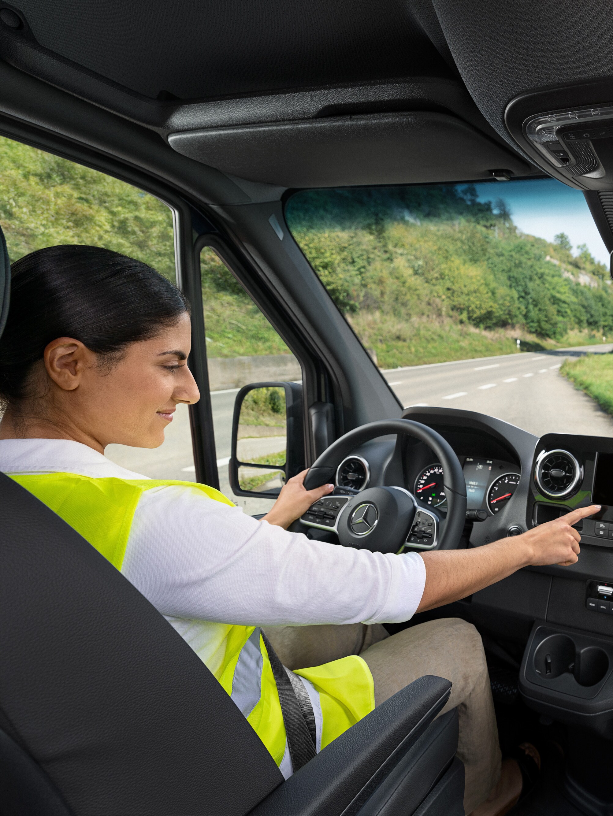 Conductora de un Mercedes-Benz Sprinter llamando a la línea directa Mercedes-Benz Service24h a través del menú de a bordo.