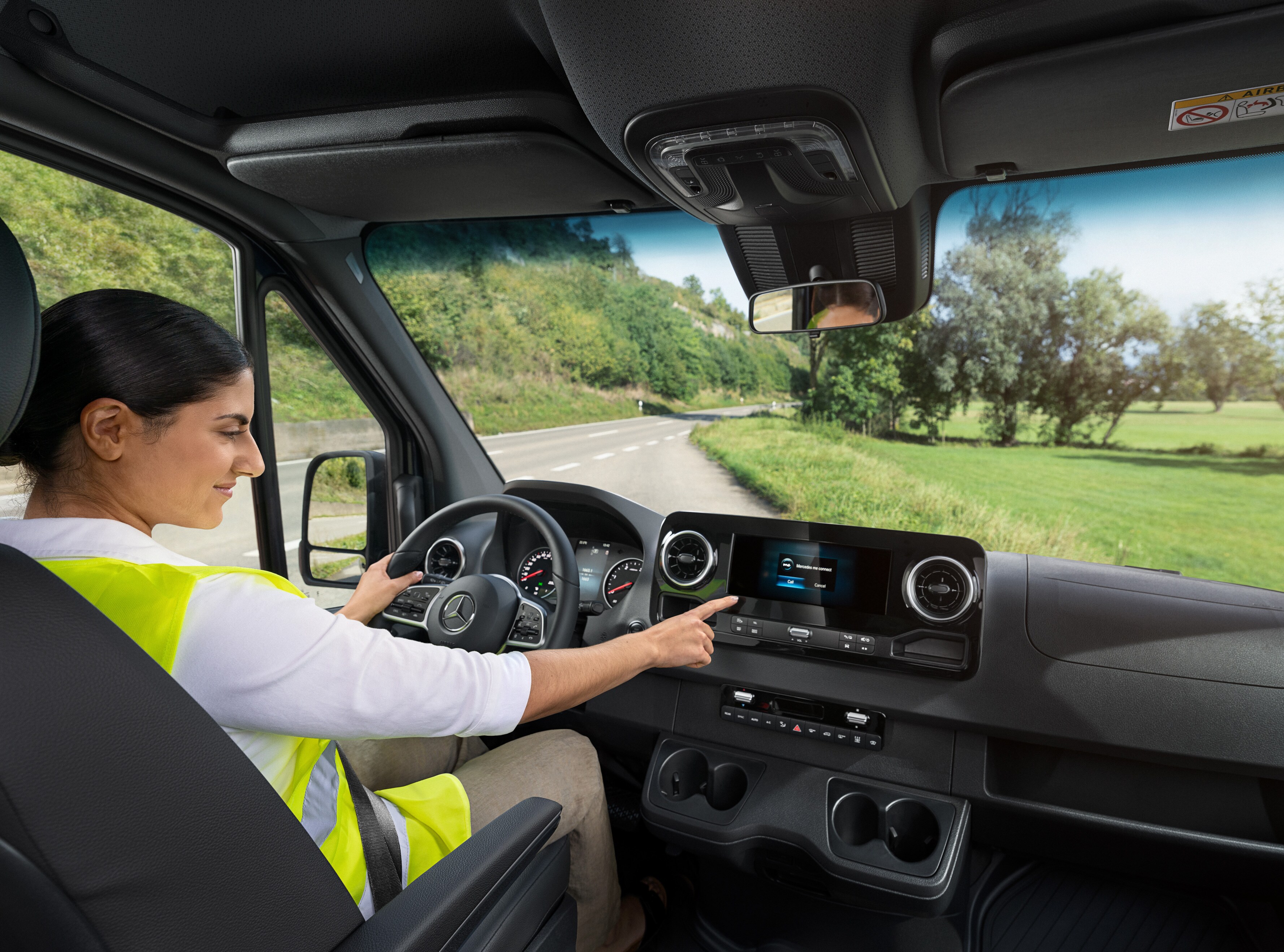 Conductora de un Mercedes-Benz Sprinter llamando a la línea directa Mercedes-Benz Service24h a través del menú de a bordo.