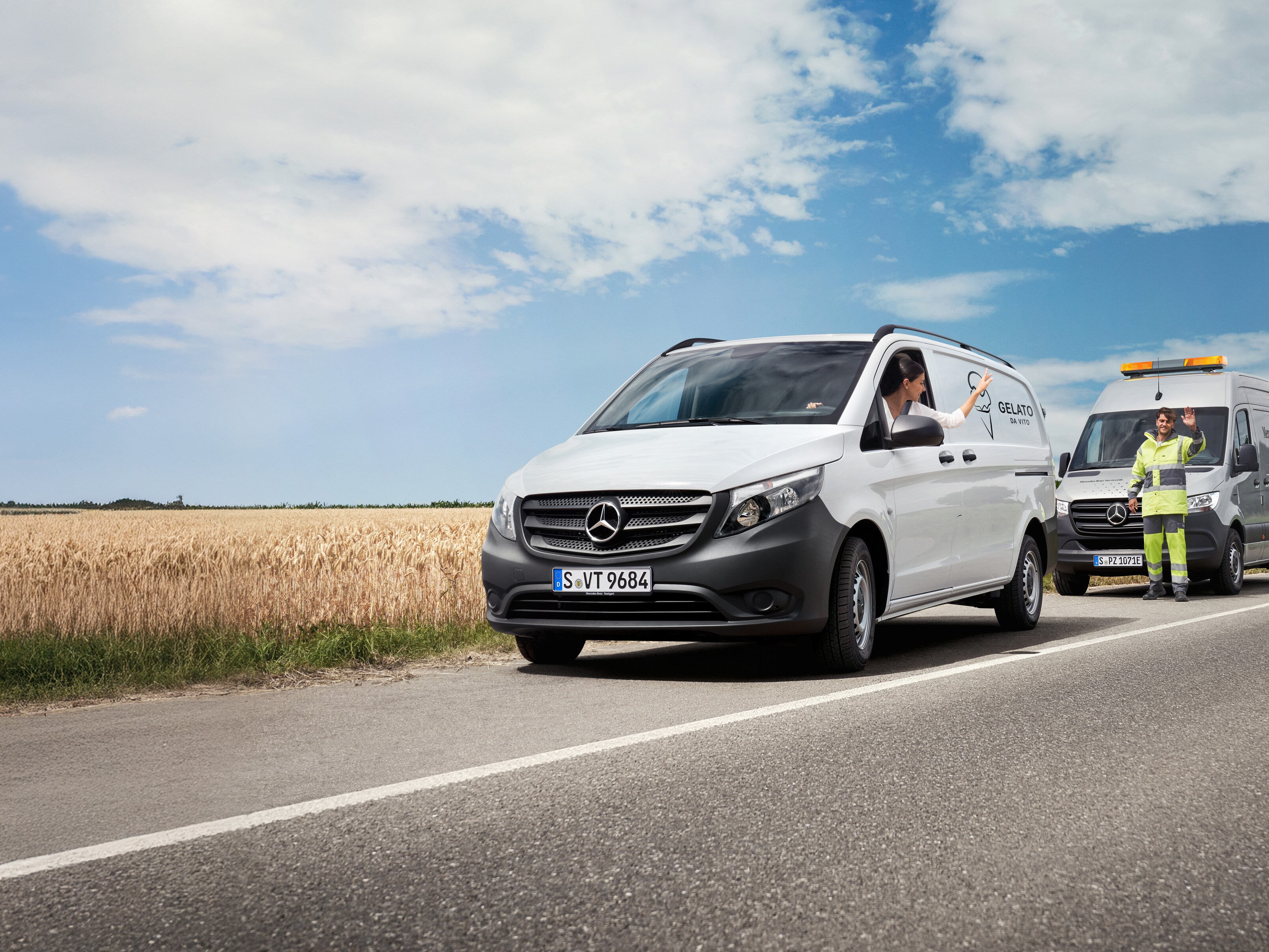 Una mujer sentada en un Mercedes-Benz Vito blanco saluda a un técnico de servicio de Mercedes-Benz al borde de la carretera.