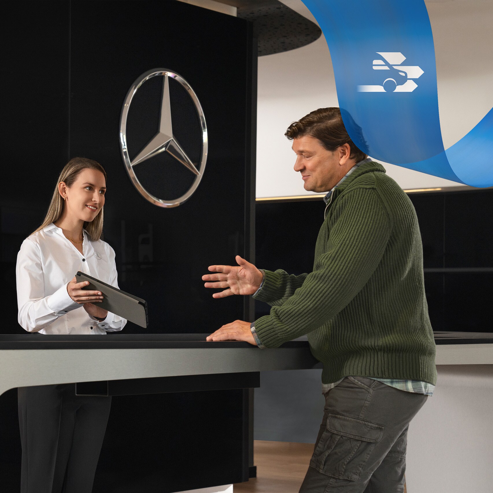 Un empleado de Mercedes-Benz atendiendo a un cliente en el mostrador de recepción.