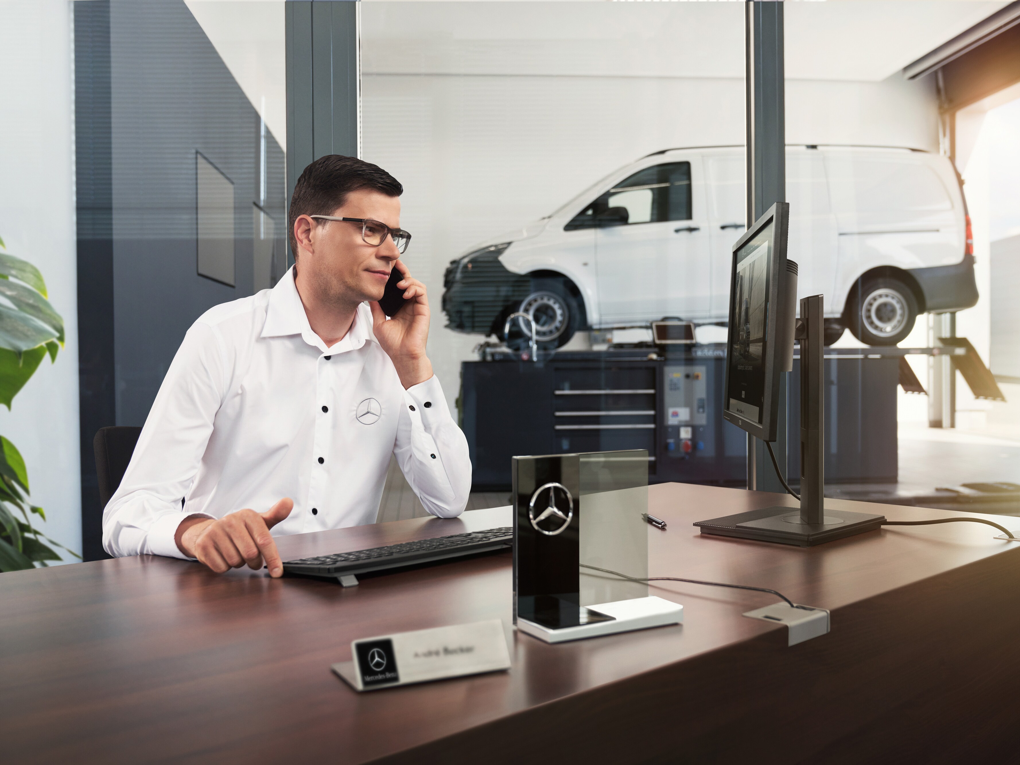 Un asesor de servicio de Mercedes-Benz hablando por teléfono en un taller.