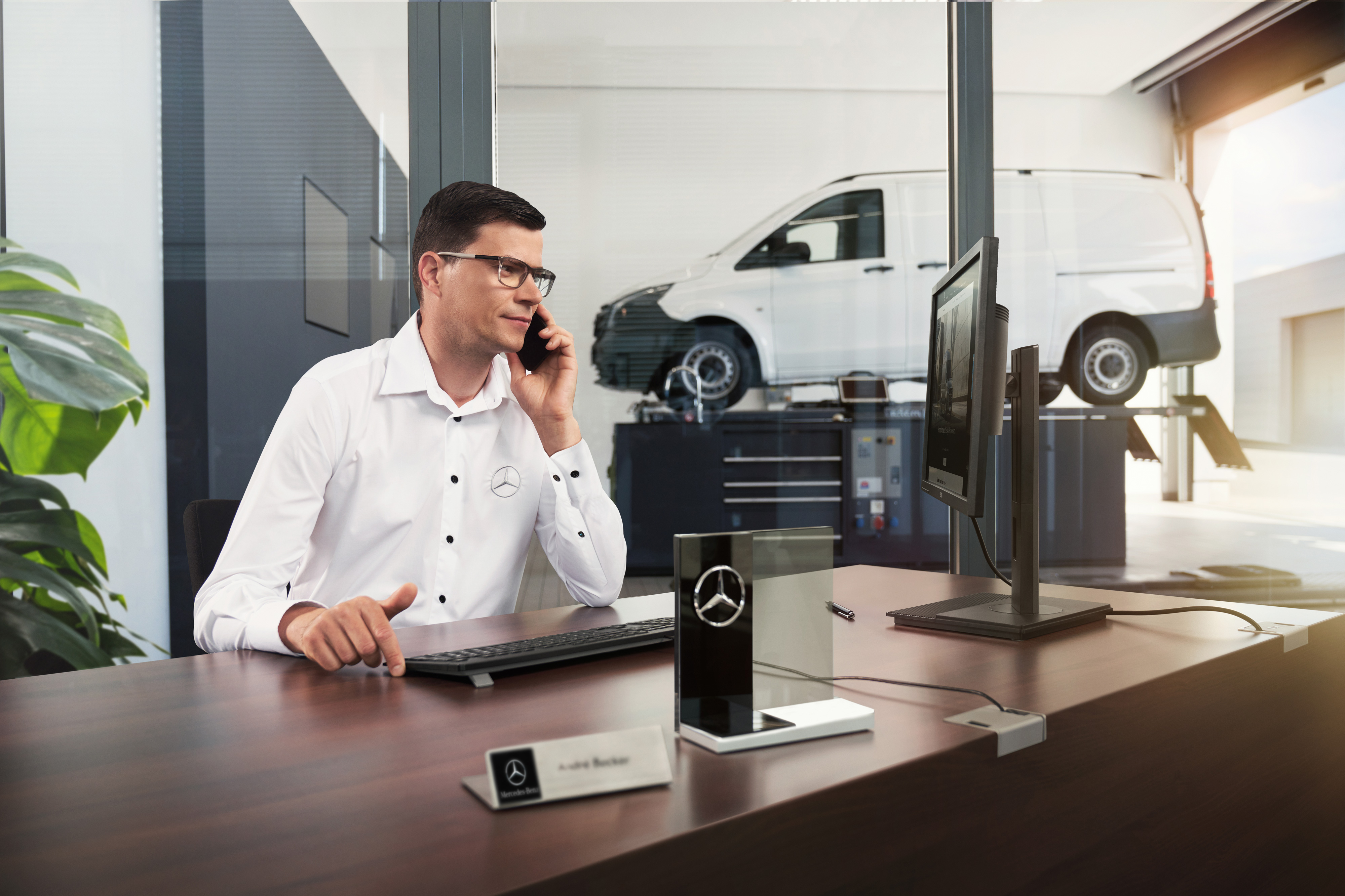 Mercedes-Benz | Conveniencia | Concesionario Oficial Un asesor de servicio de Mercedes-Benz hablando por teléfono en un taller.