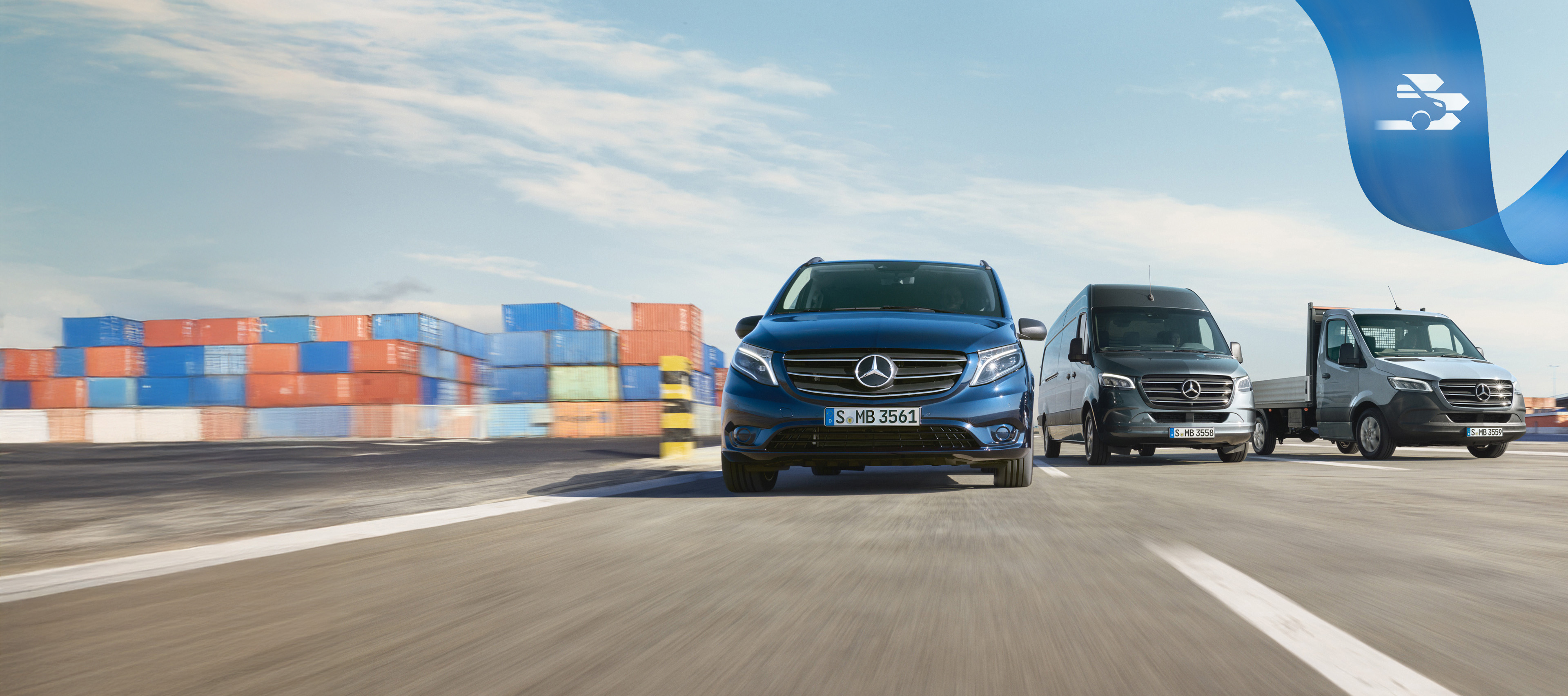 Mercedes Benz | MobiloVan Conveniencia Una serie de furgones Mercedes-Benz en una carretera con contenedores de transporte al fondo.
